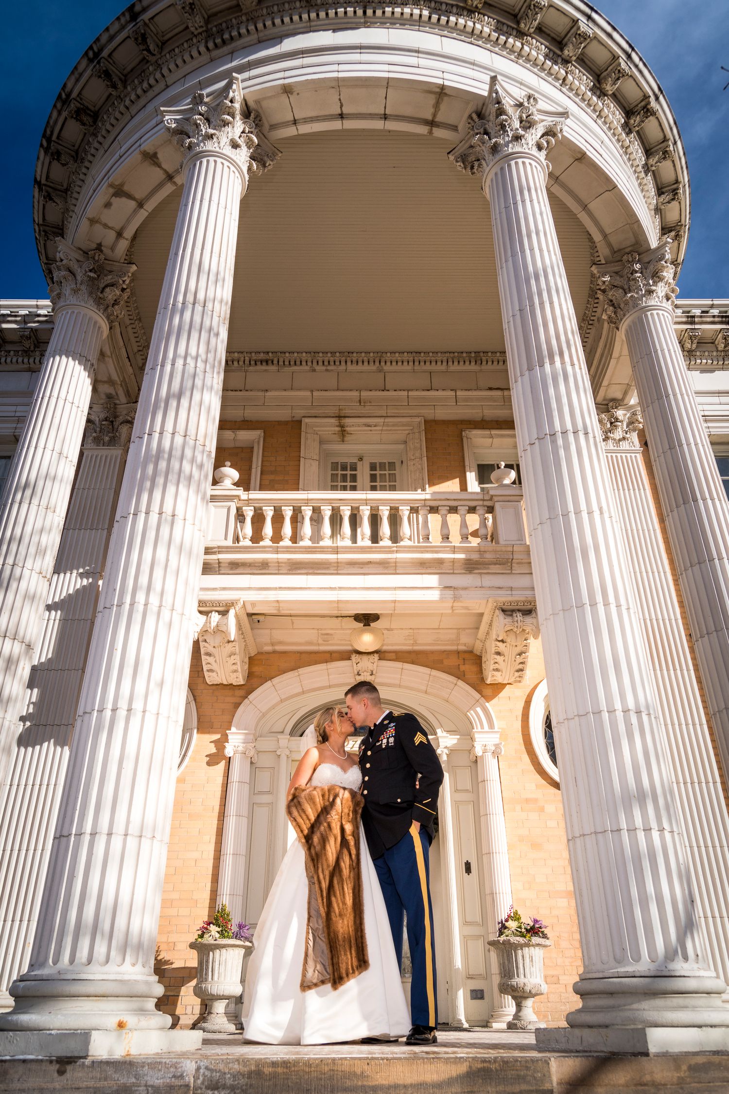 Romantic wedding portrait under grand classical columns of historic building.