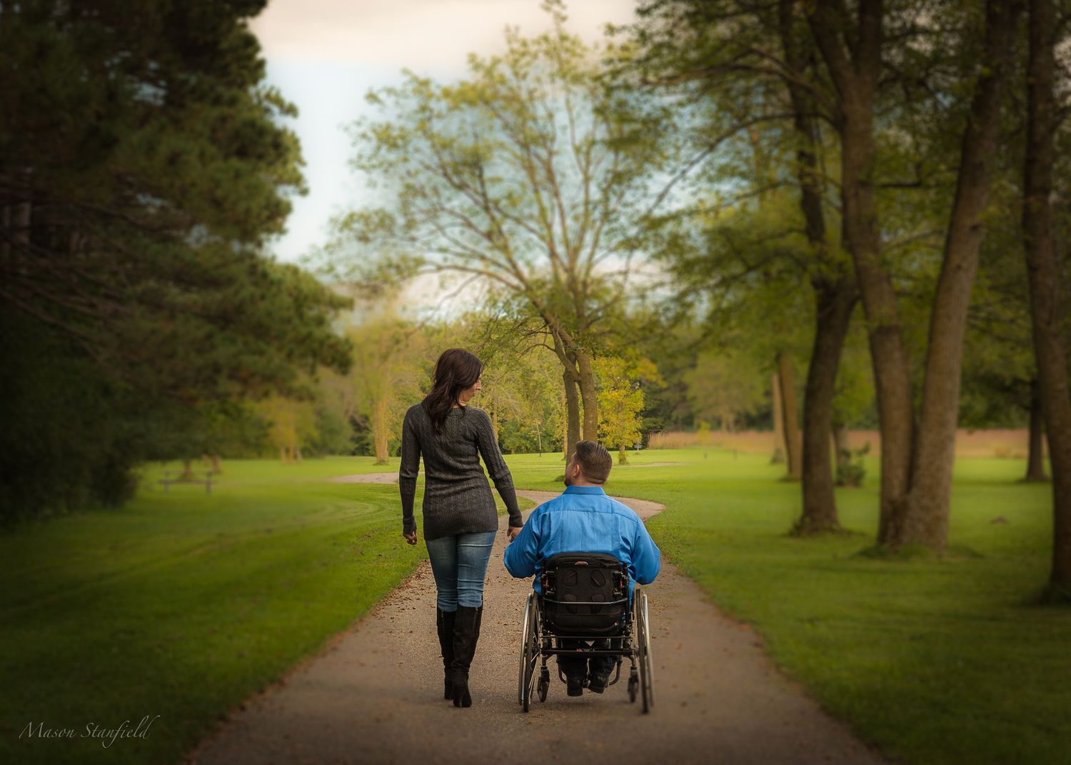 Two people walking together on a tree-lined path in a serene park setting.