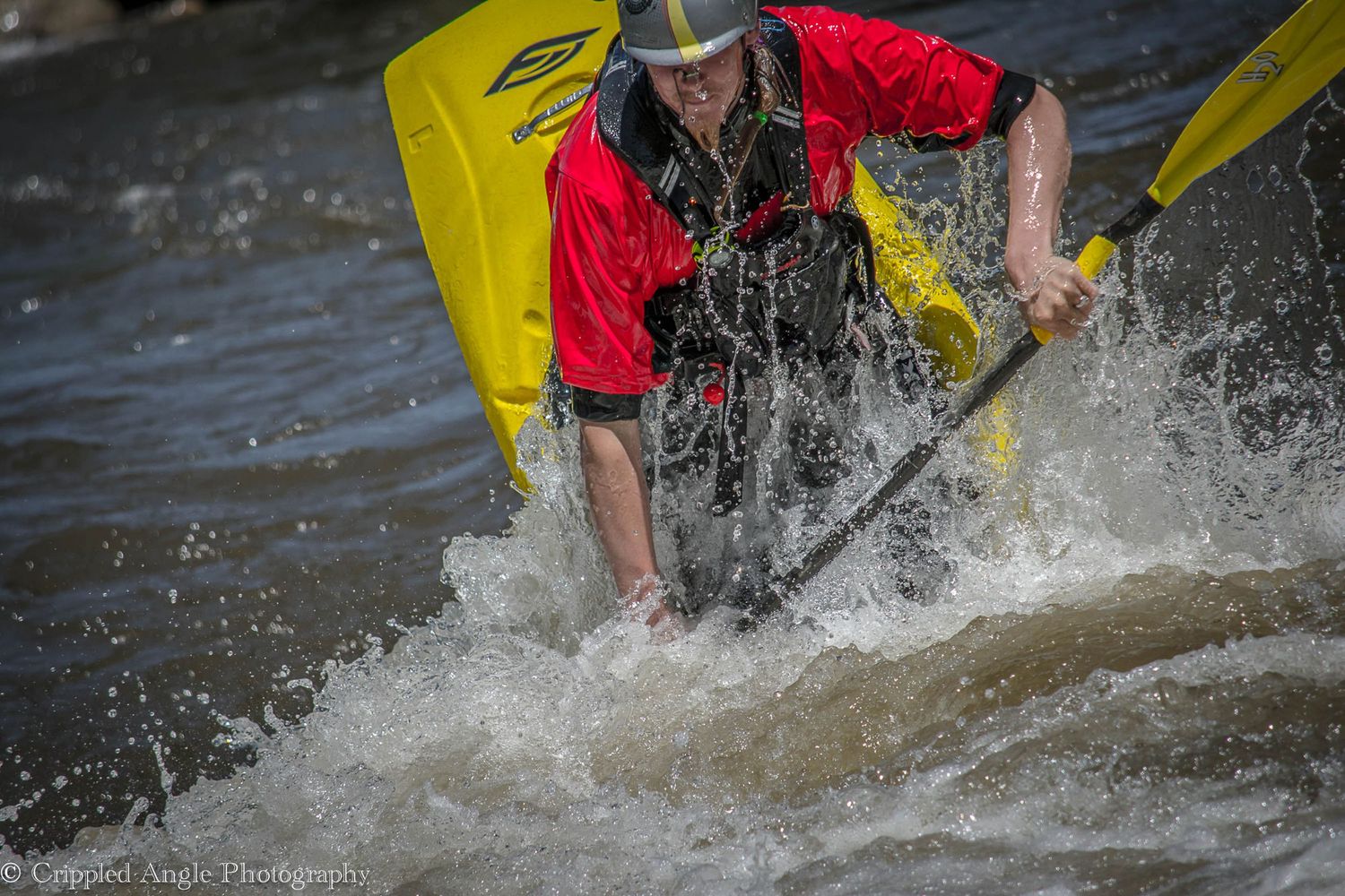 Kayaker navigating through splashing white water rapids in yellow boat.