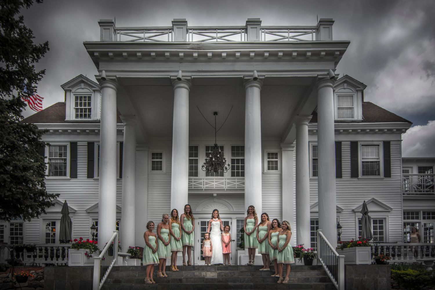 Wedding party posed in front of mansion with white columns in dramatic black and white.
