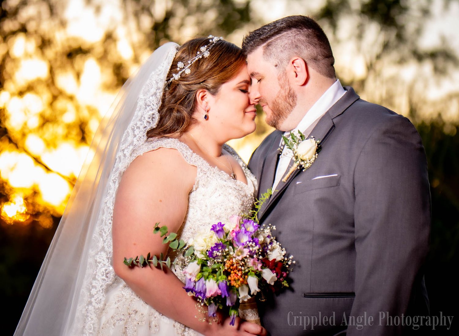 A sunset wedding portrait with a colorful wildflower bouquet and soft golden lighting.