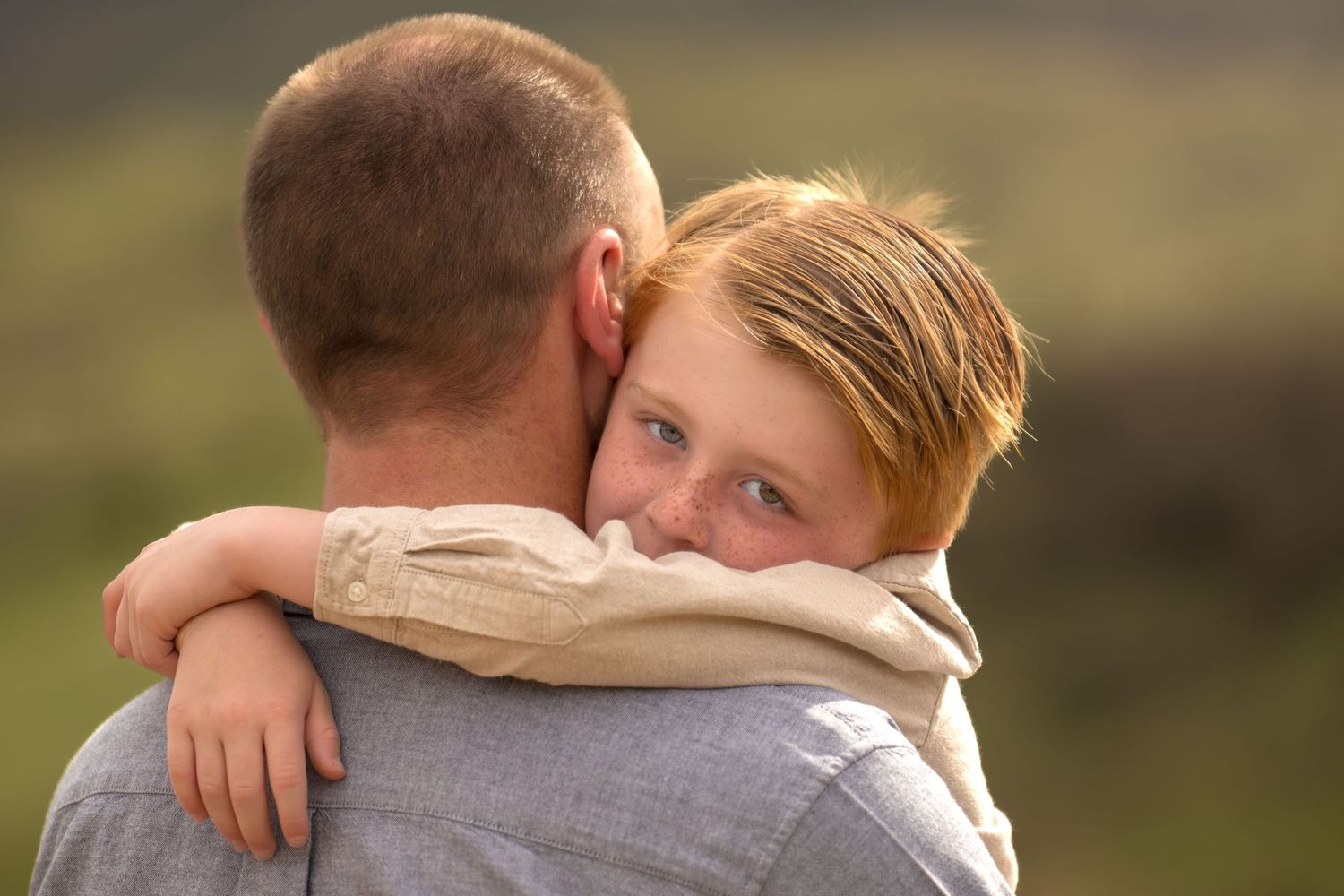 Heartwarming embrace between parent and child sharing an emotional outdoor moment in natural sunlight.