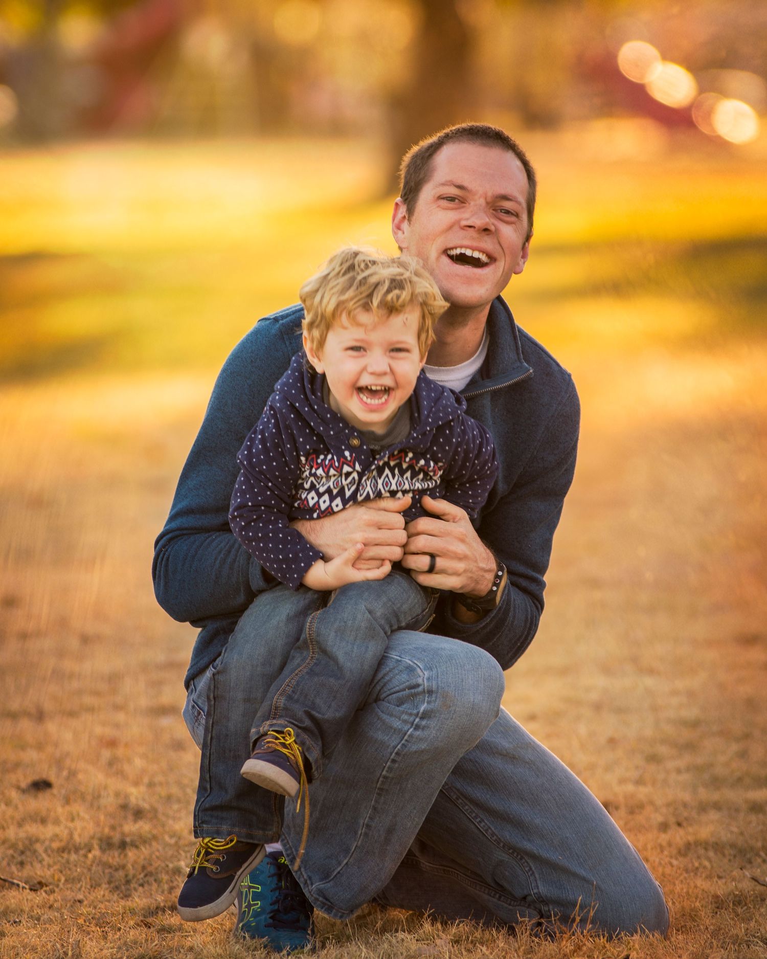 Parent and child share laughter during outdoor sunset photo session.