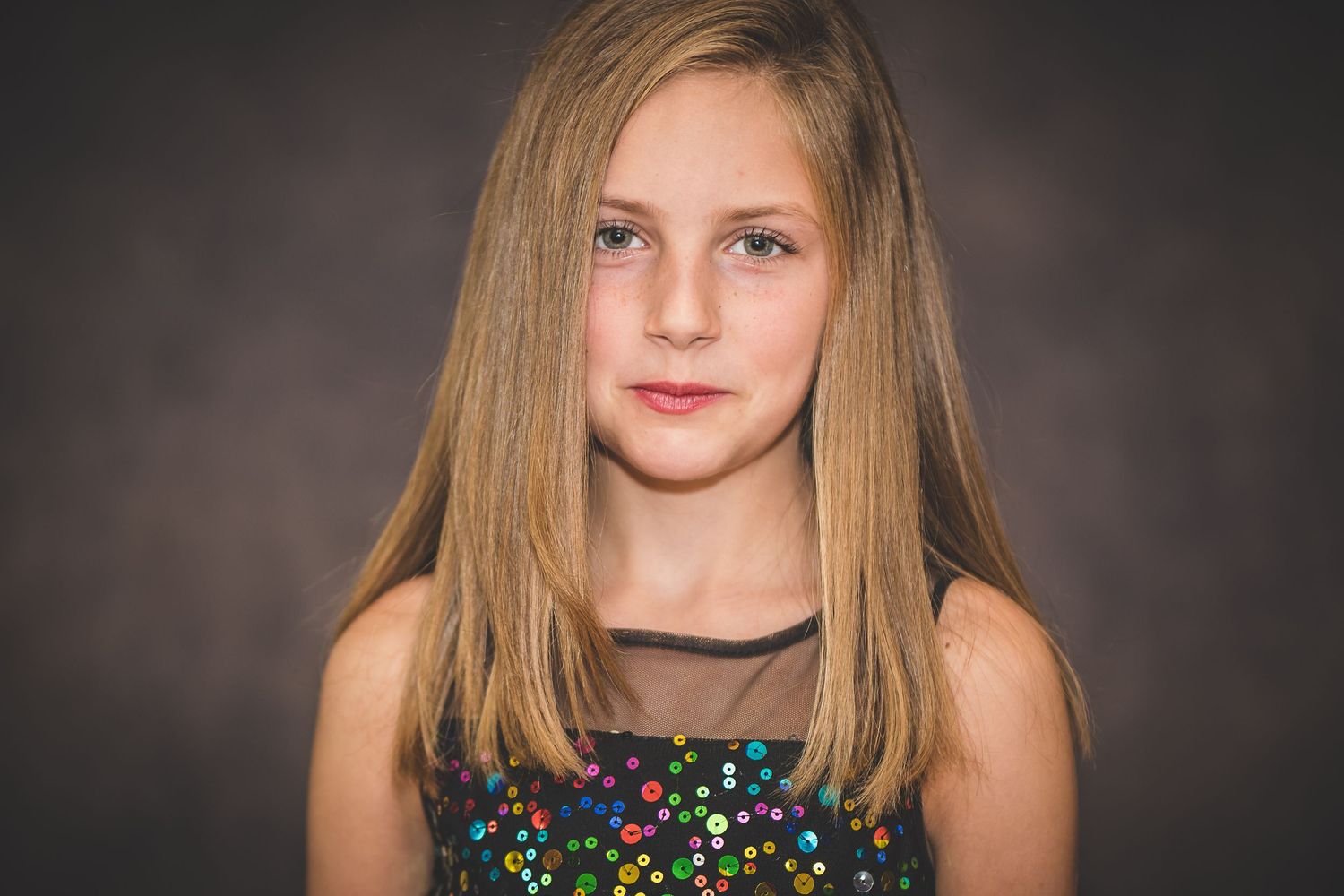 Studio portrait featuring sparkly formal attire against dark backdrop.
