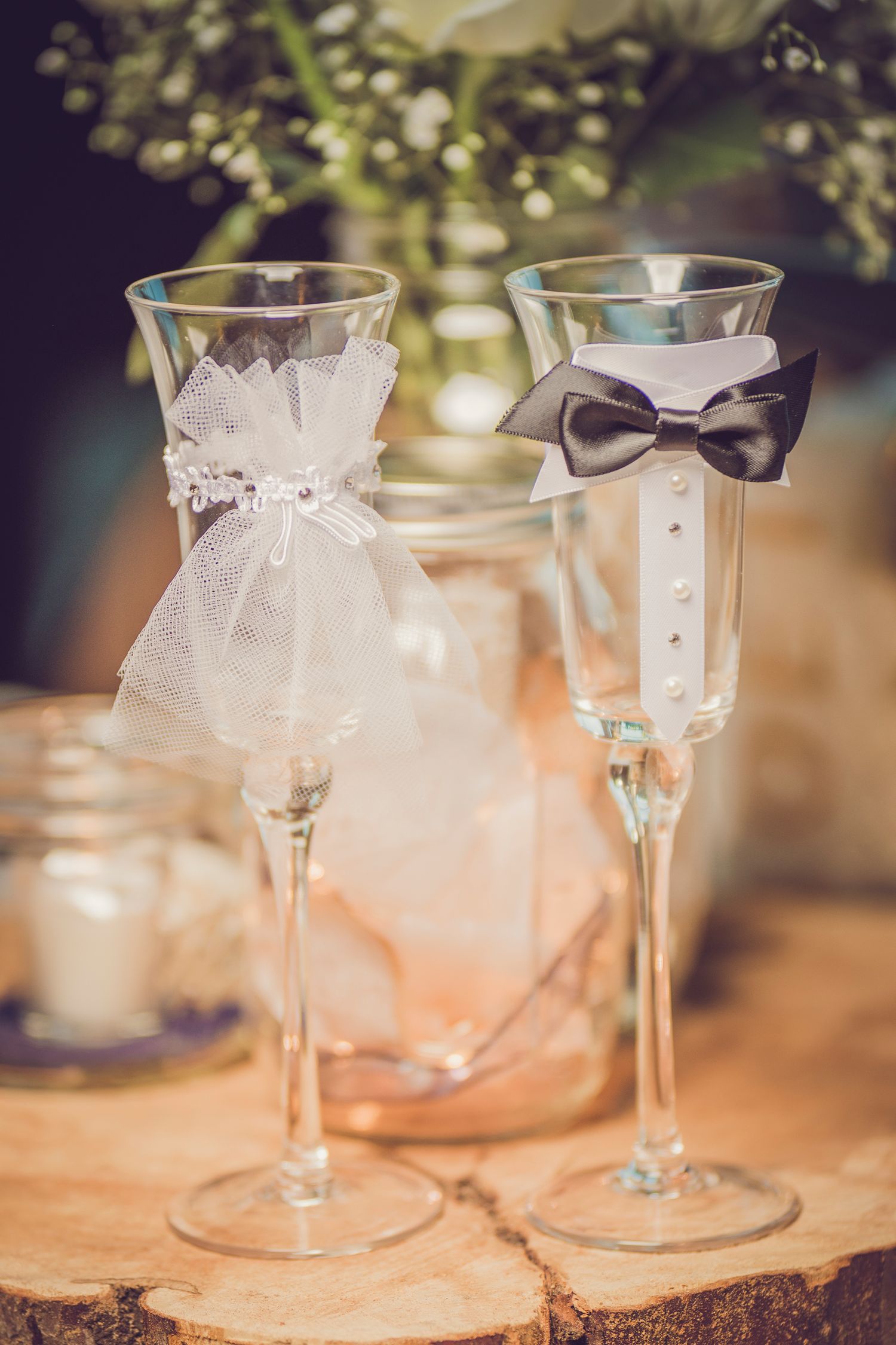 Wedding champagne flutes decorated with bride and groom designs on rustic wood slice.