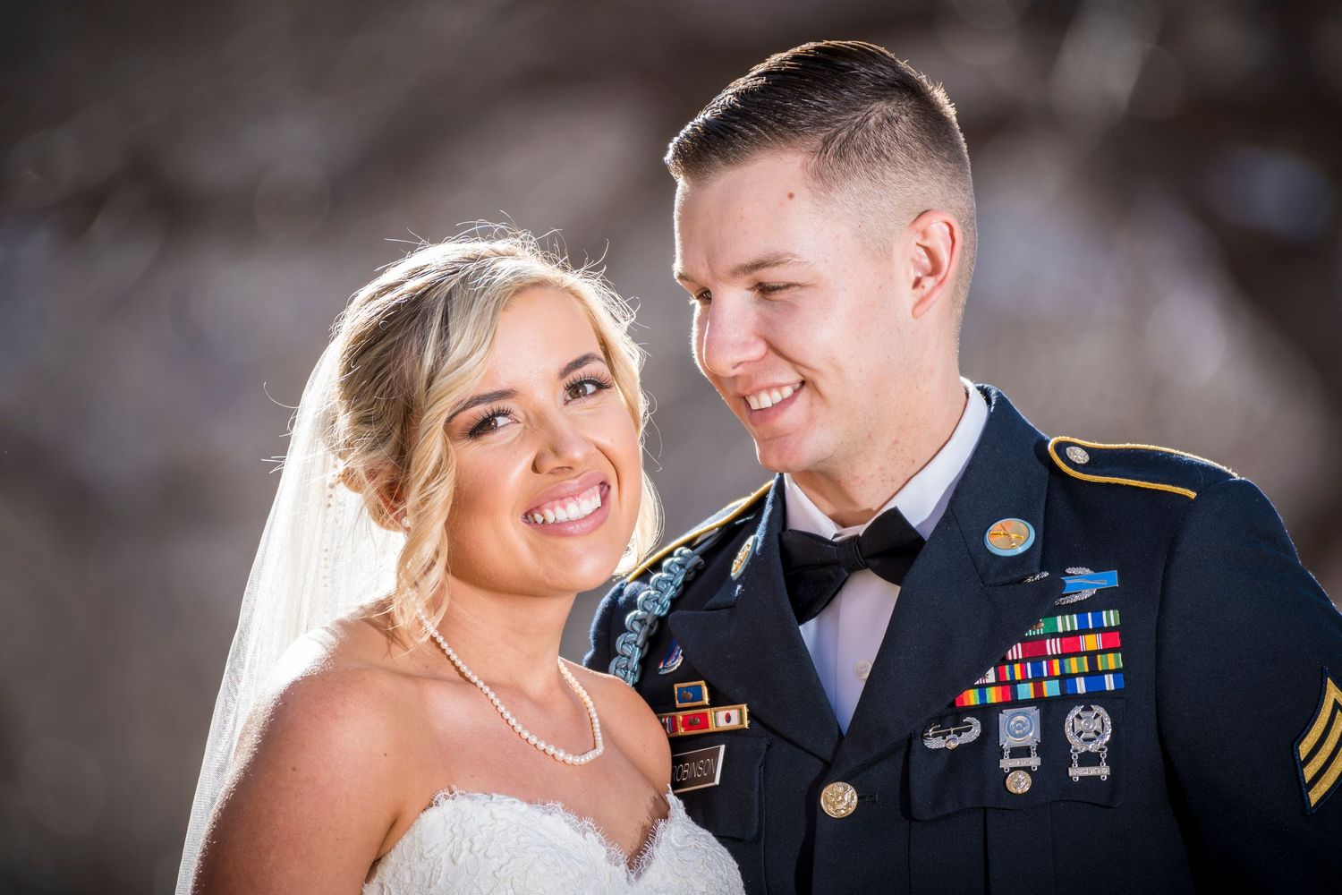 Military wedding portrait outdoors with decorative medals visible on formal uniform.