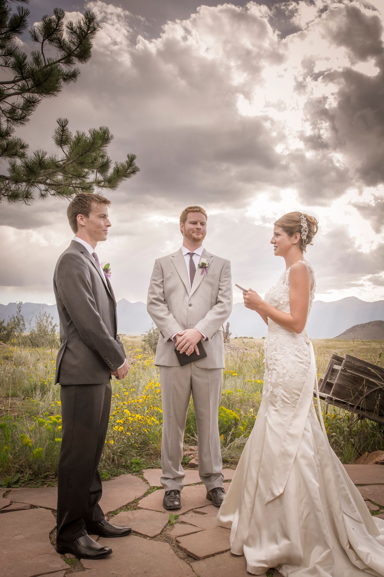 Outdoor wedding ceremony with dramatic cloudy sky and mountain backdrop.