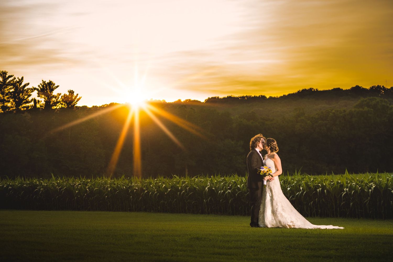 Silhouette of couple embracing during golden sunset in countryside.