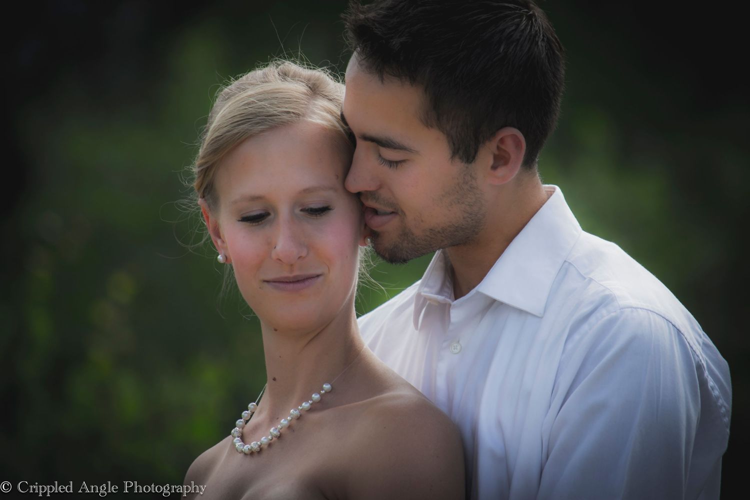 Romantic outdoor portrait of a couple in wedding attire sharing an intimate moment.