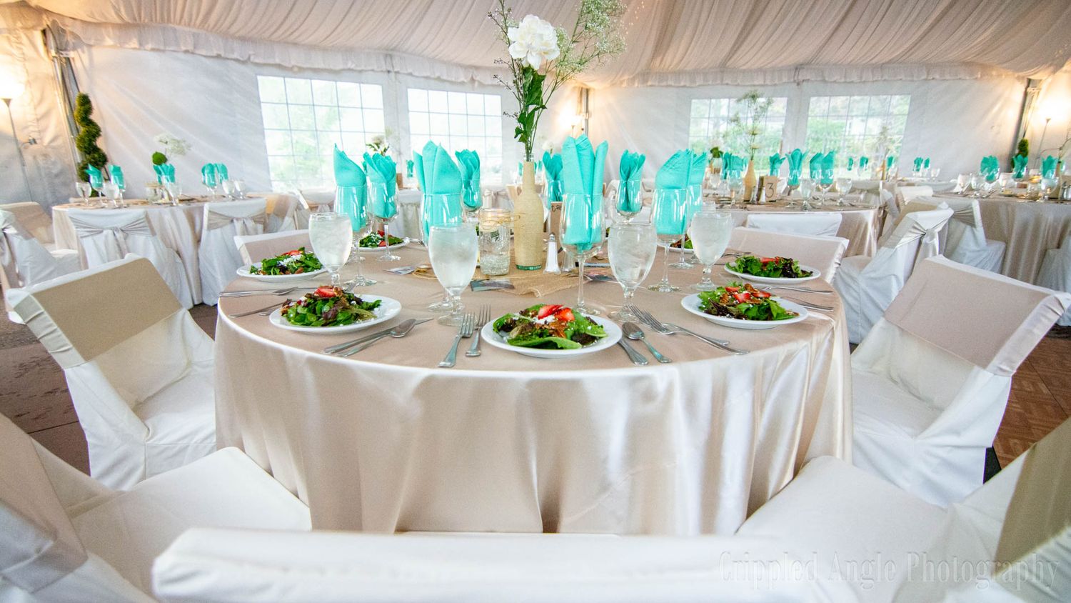 Elegant wedding reception table setting with turquoise accents and white linens.