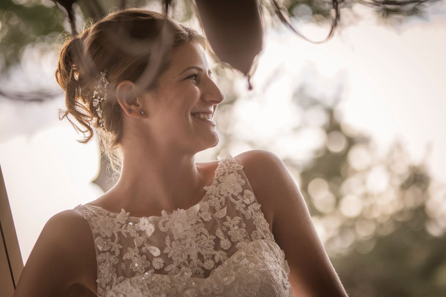 Bride in lace dress smiling in soft natural lighting.