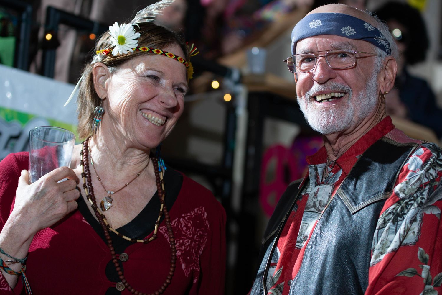 A couple in festive dress laughing together at a carnival celebration.