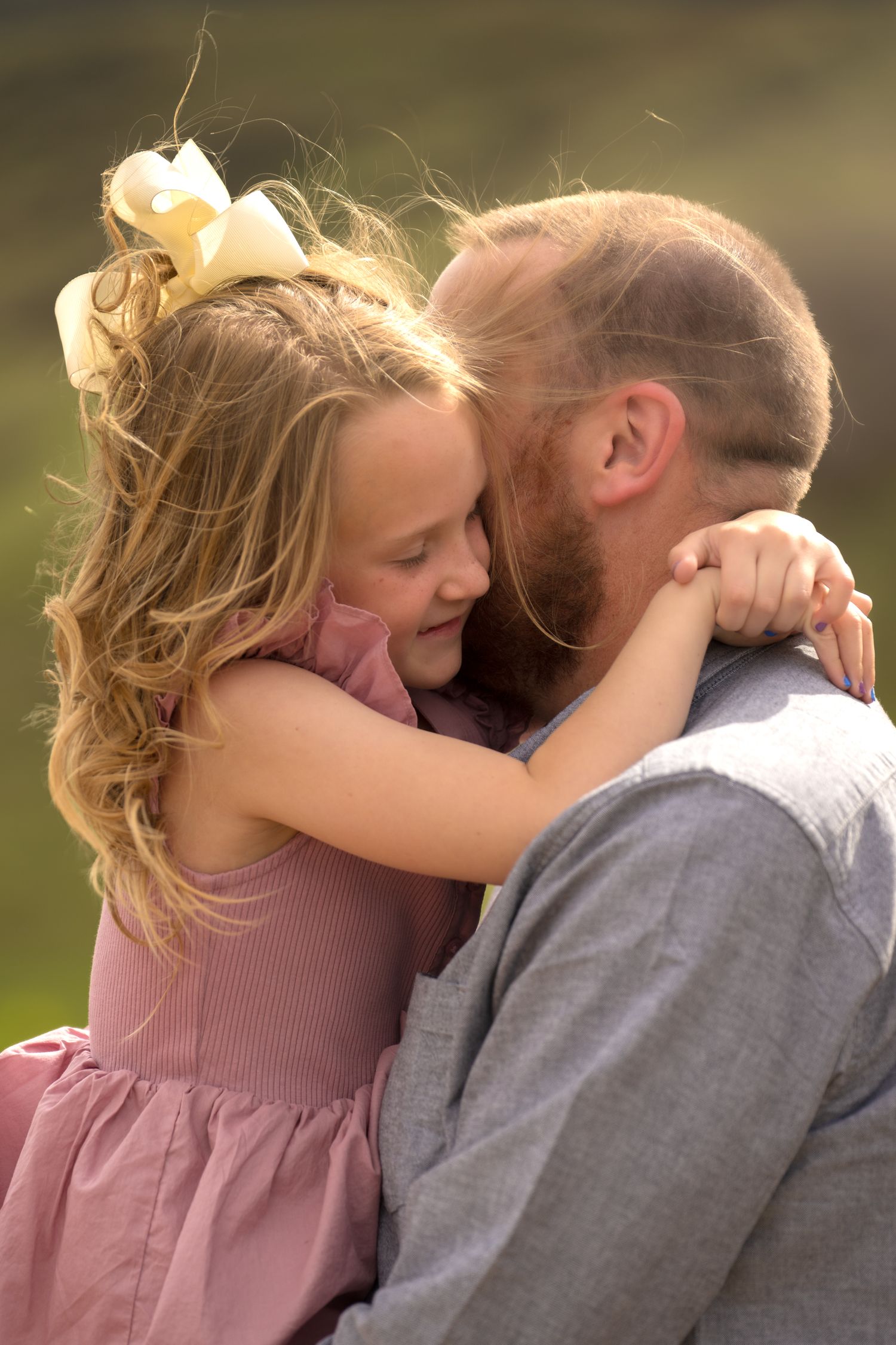 A tender moment shared between parent and child embracing outdoors in soft natural lighting.