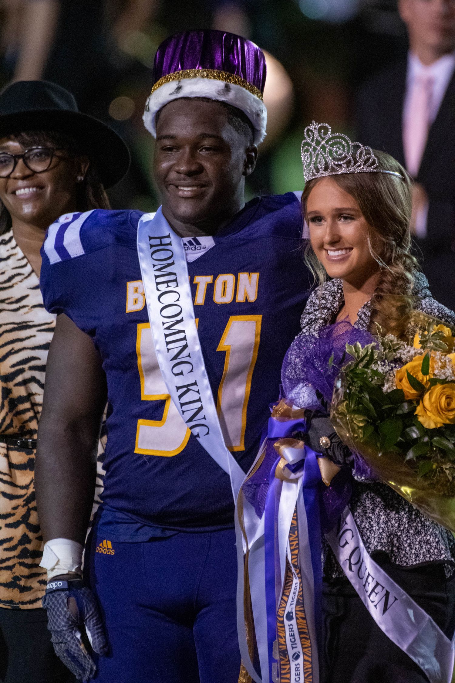 Homecoming king and queen wearing crown and tiara at school football celebration.
