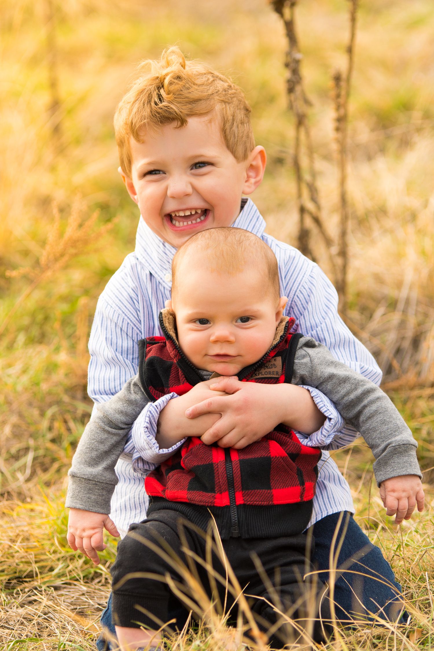 Two siblings share a joyful moment together in autumn grass.