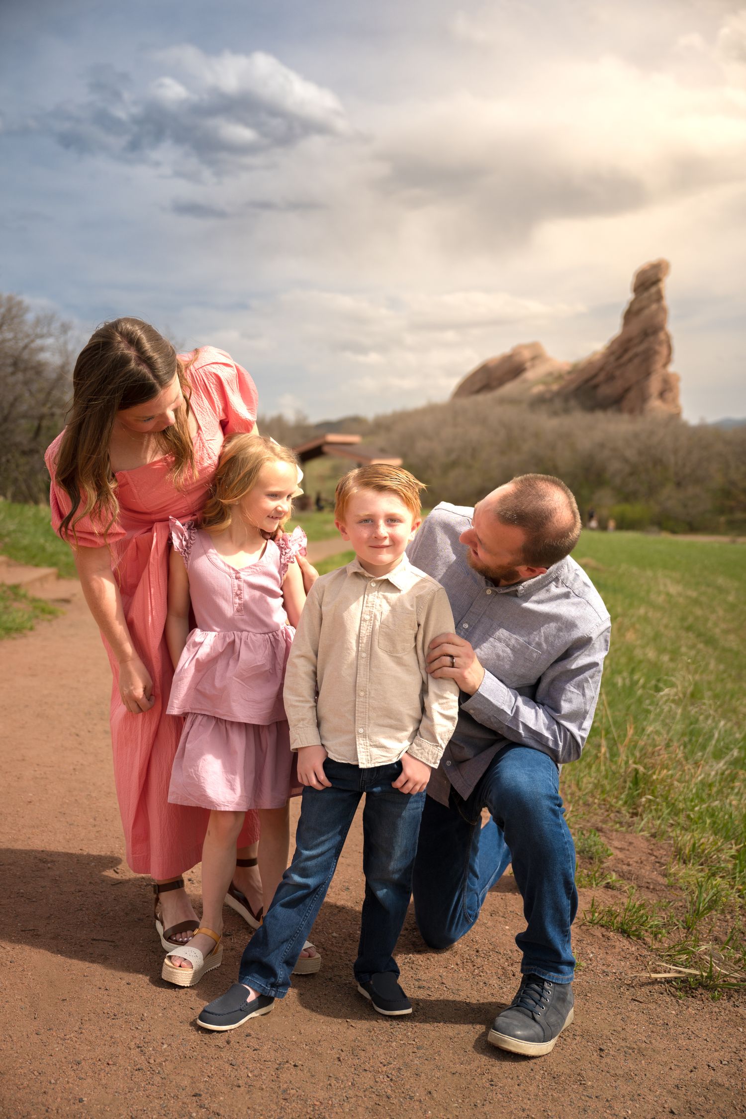 A happy family enjoying a playful moment together on a dirt path with scenic rock formations in the background.