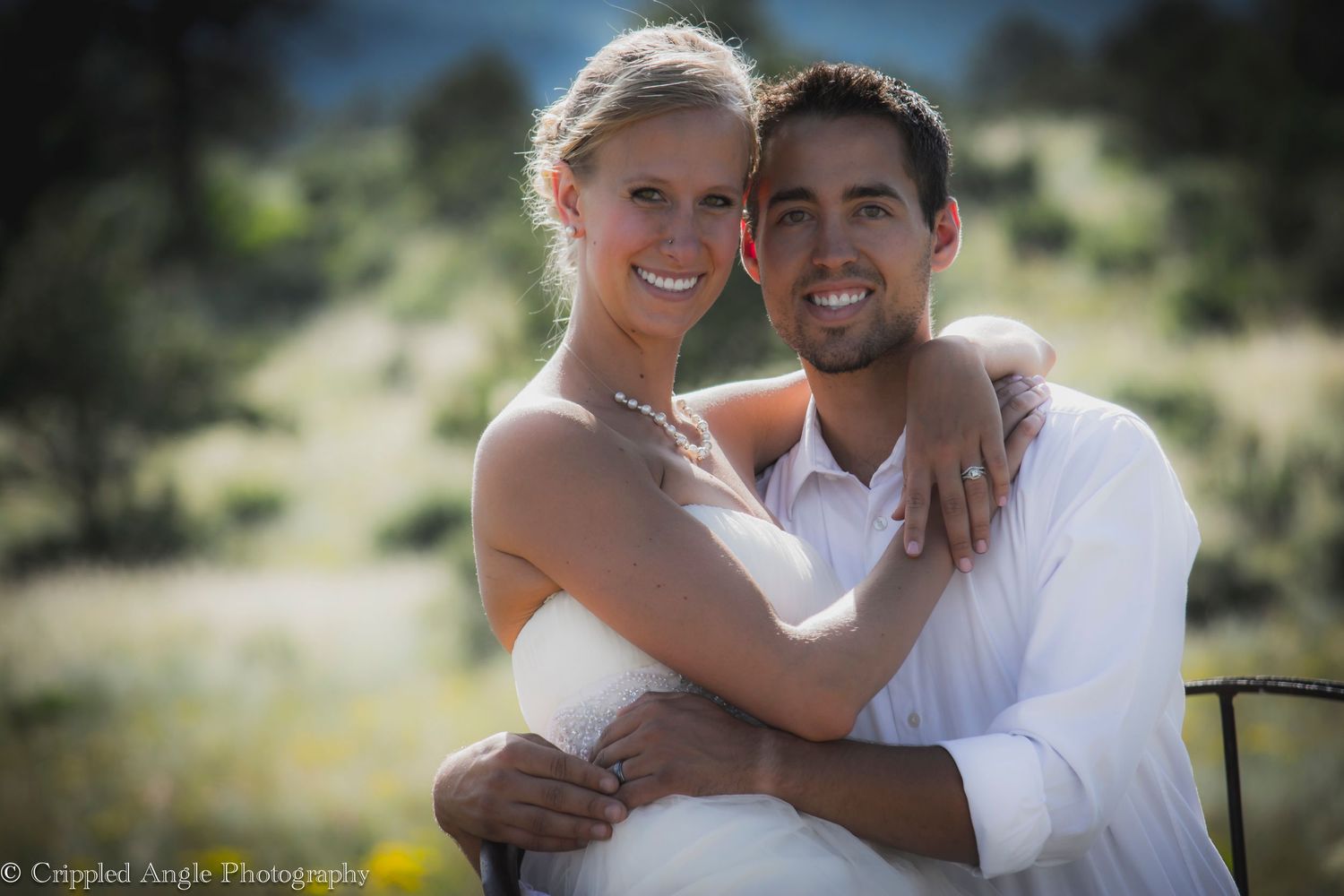 Bride and groom sharing a joyful embrace in sunny outdoor setting.