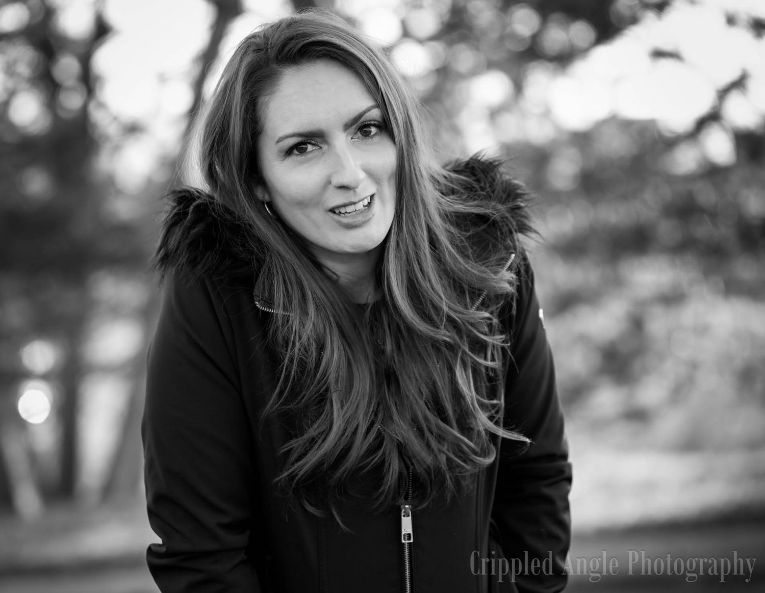 Black and white outdoor portrait showing a candid smile and long flowing hair.