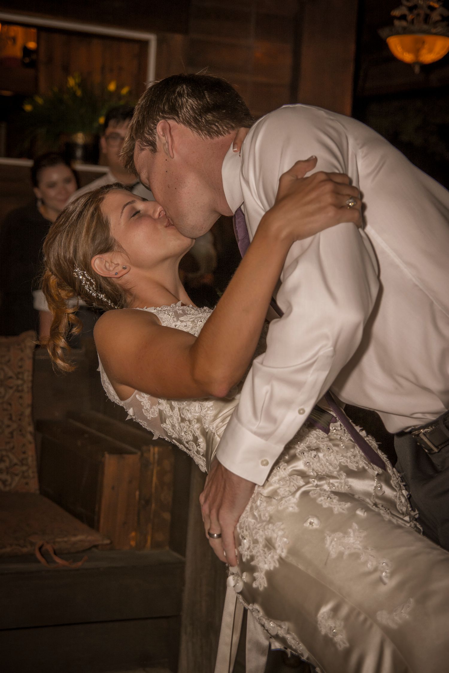A romantic dip kiss moment during a wedding reception.