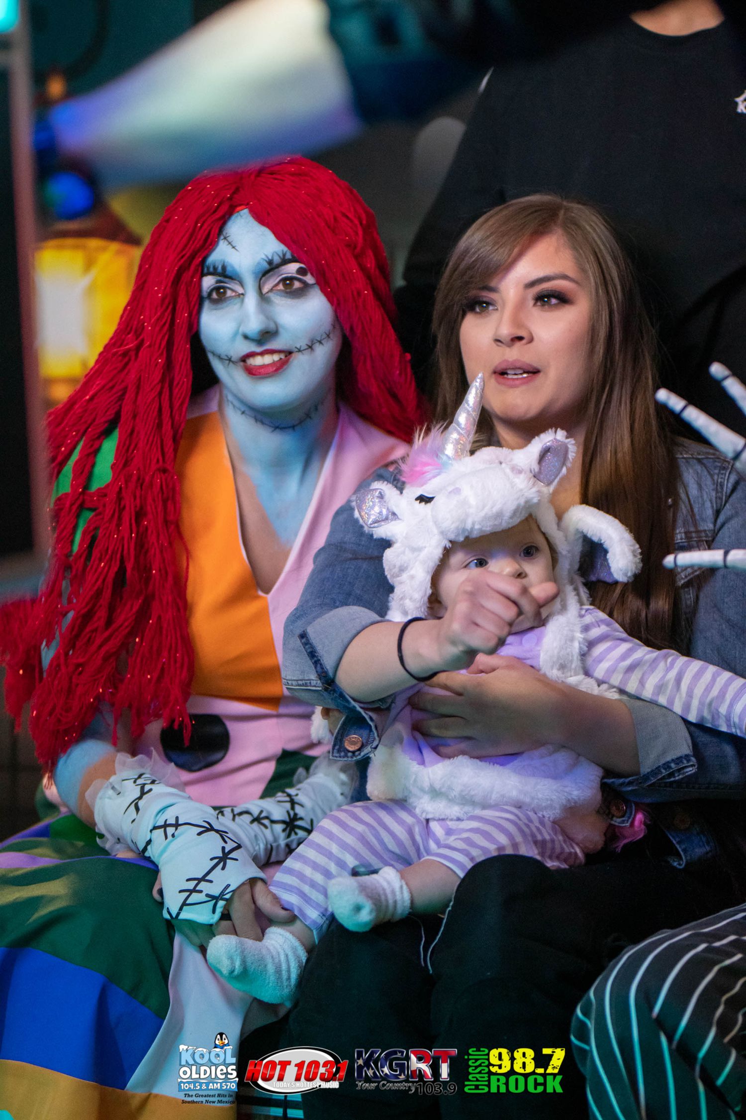 Cosplay characters in colorful outfits at a convention with one holding a plush toy.