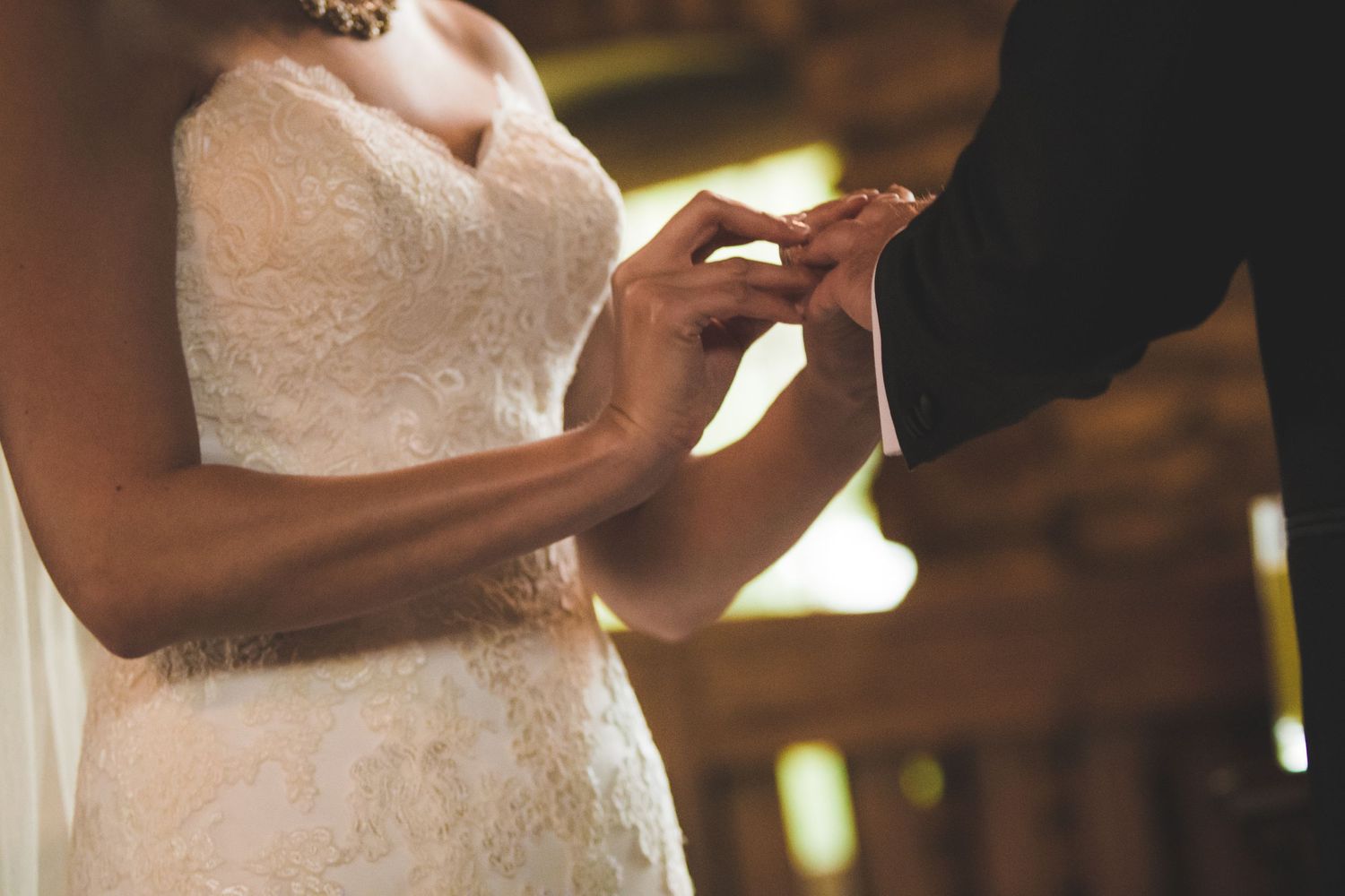 Close-up shot of hands exchanging wedding rings during ceremony.