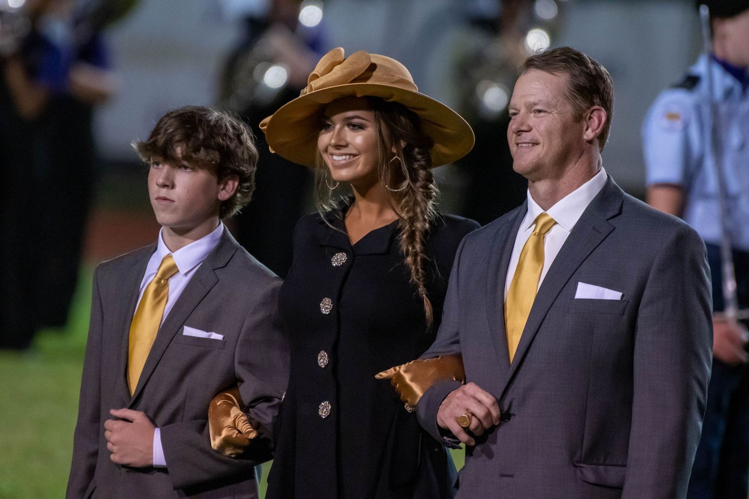 Well-dressed family poses together during formal outdoor event.