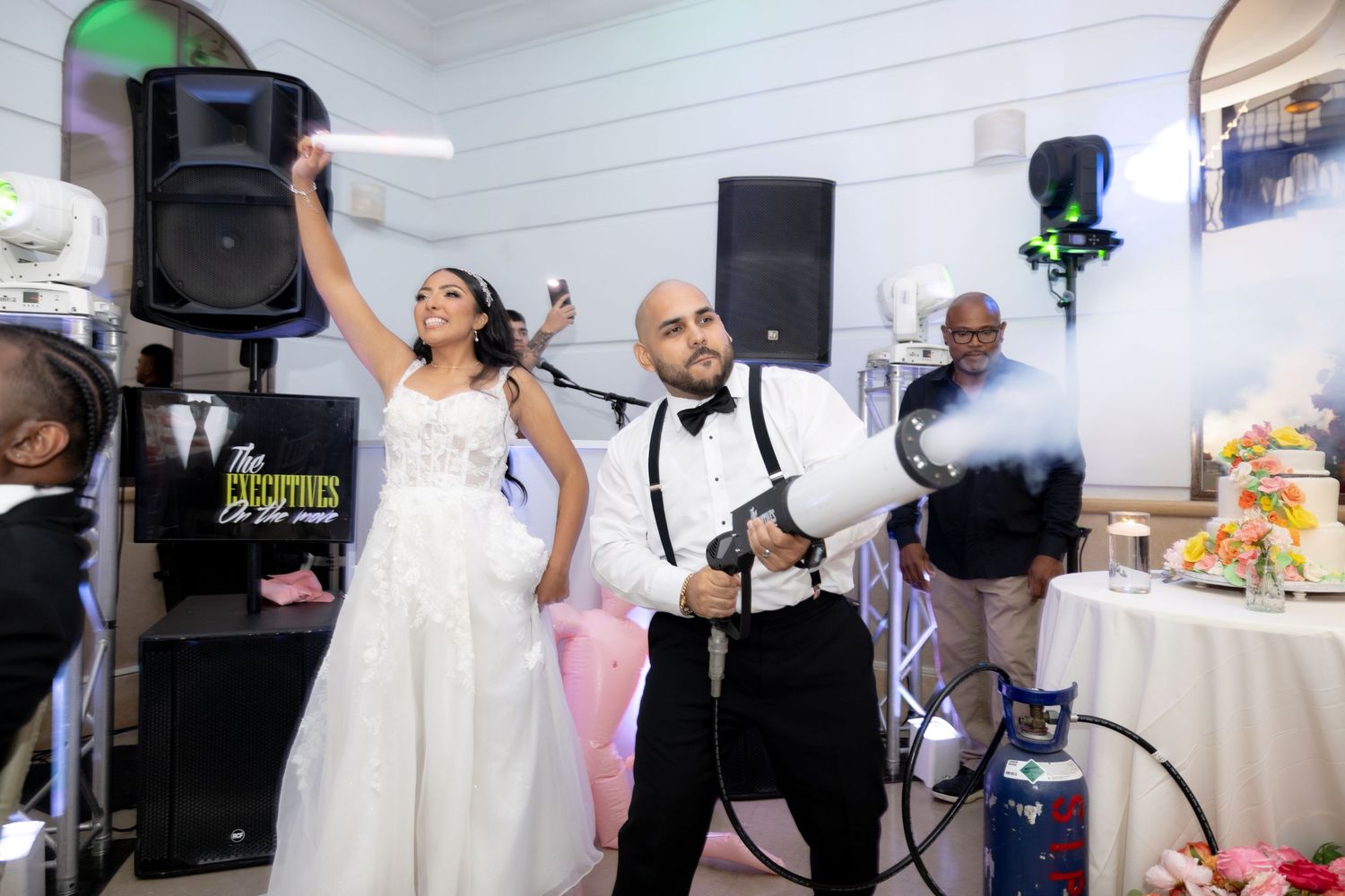 Wedding photographers work with lighting equipment to capture dance floor moments at a reception.