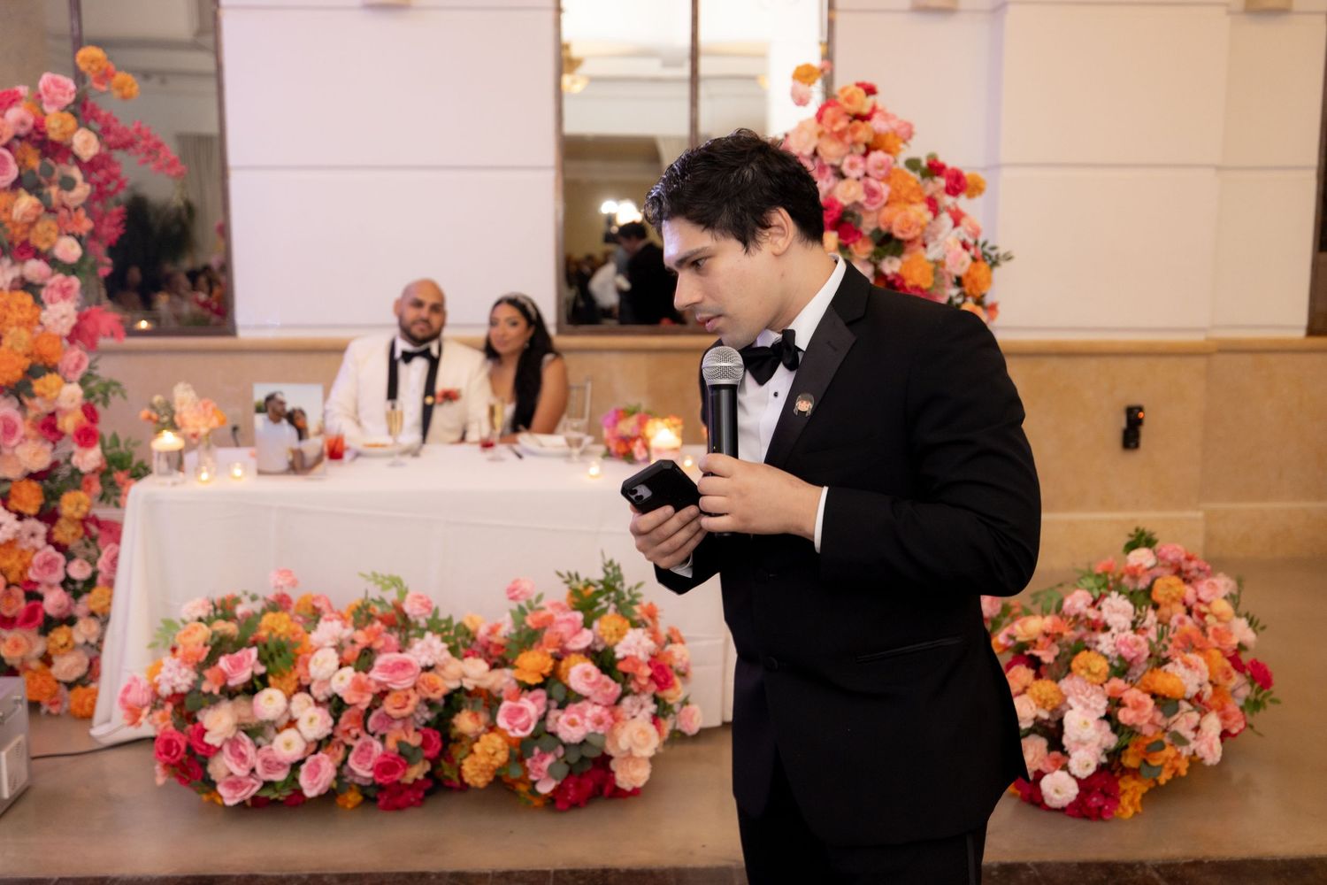 Wedding photographers capture candid moments during a reception with pink floral decorations.