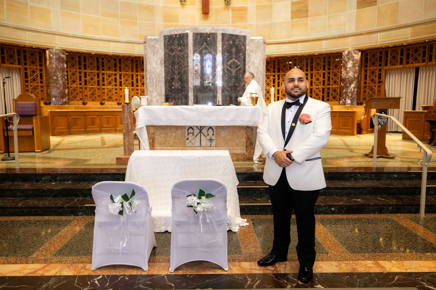 Wedding ceremony venue with white chair covers and decorative aisle setup in an elegant church interior.