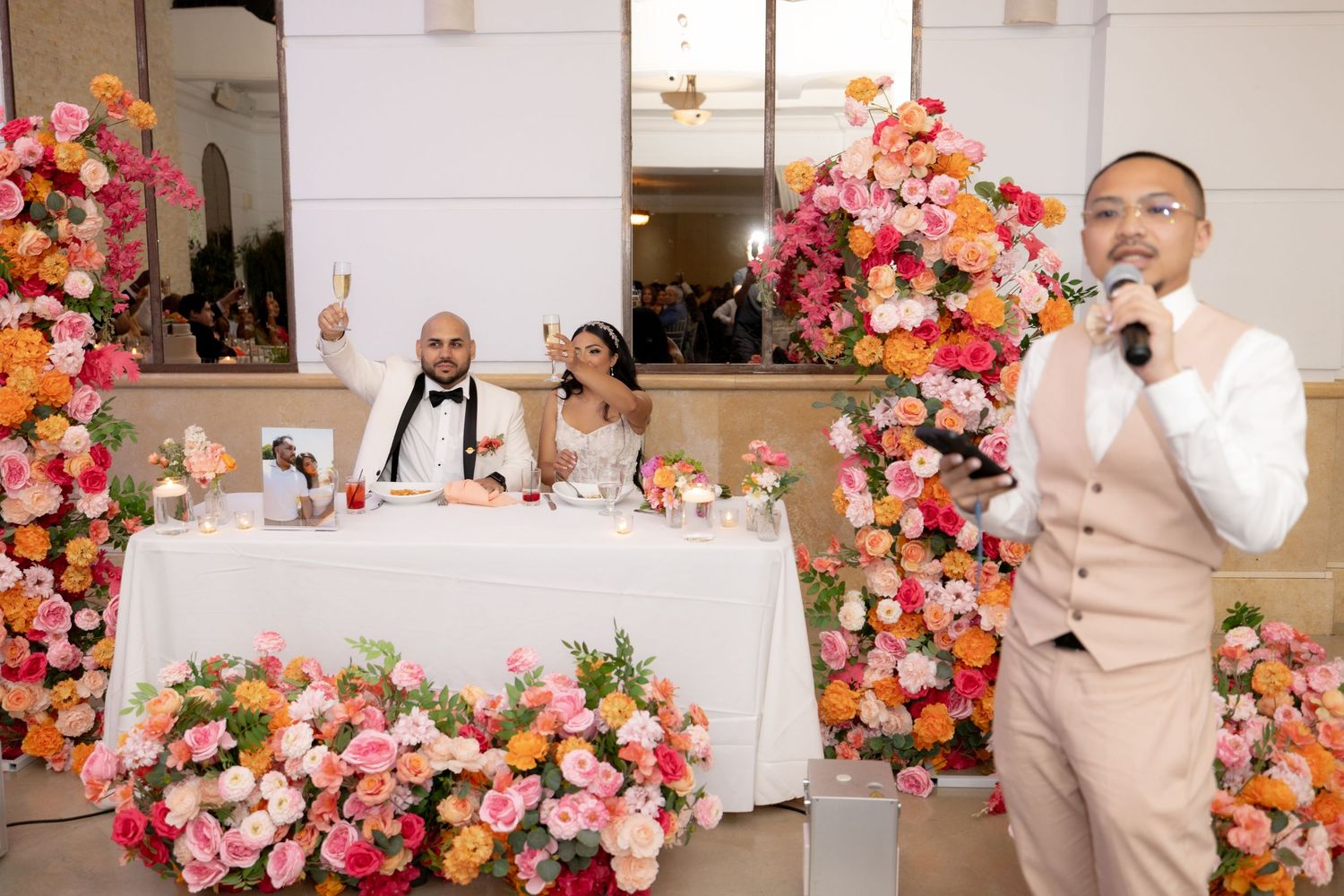 Wedding reception venue decorated with vibrant pink and coral flower arrangements.