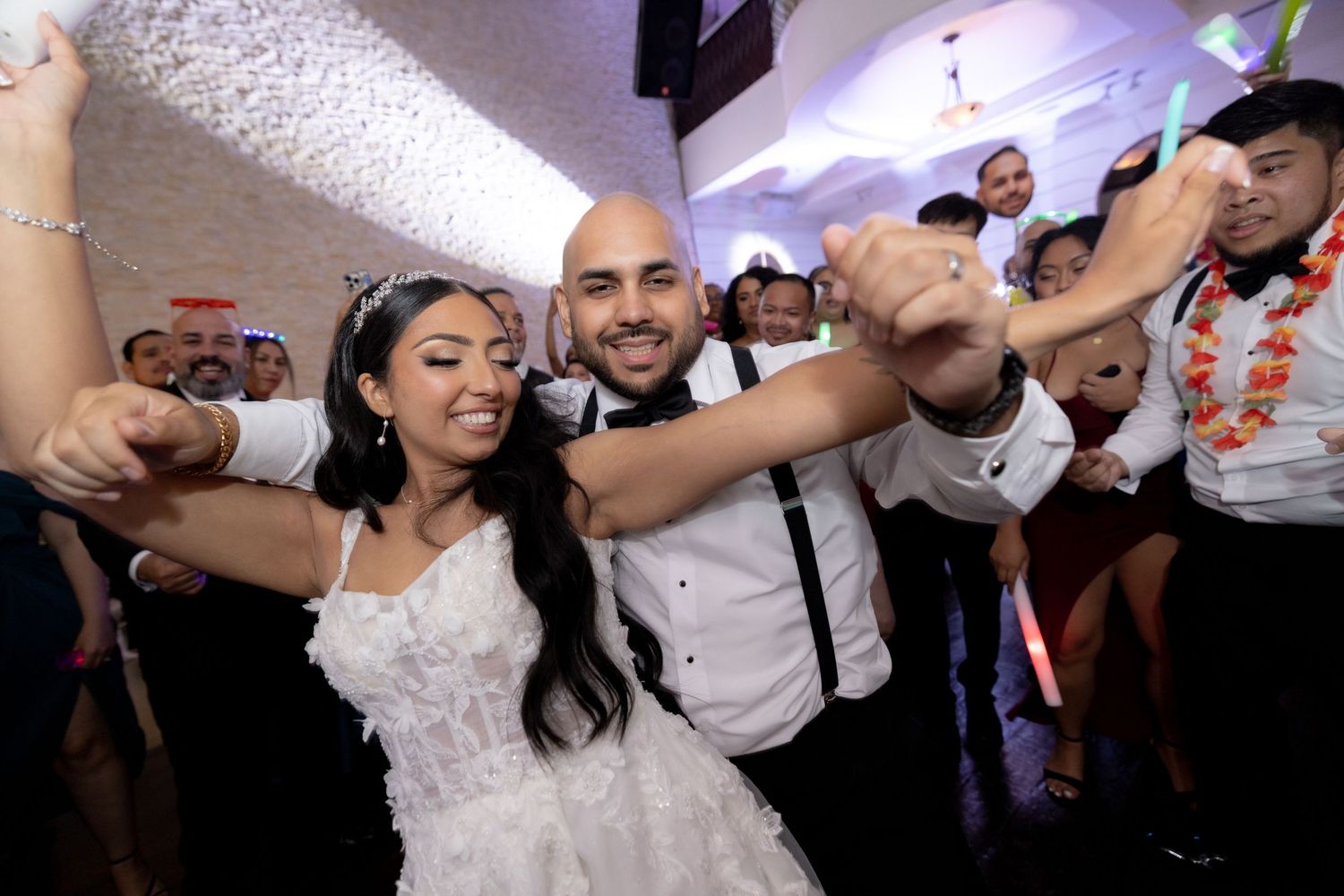 Wedding celebration on dance floor with guests dancing and enjoying the festivities.