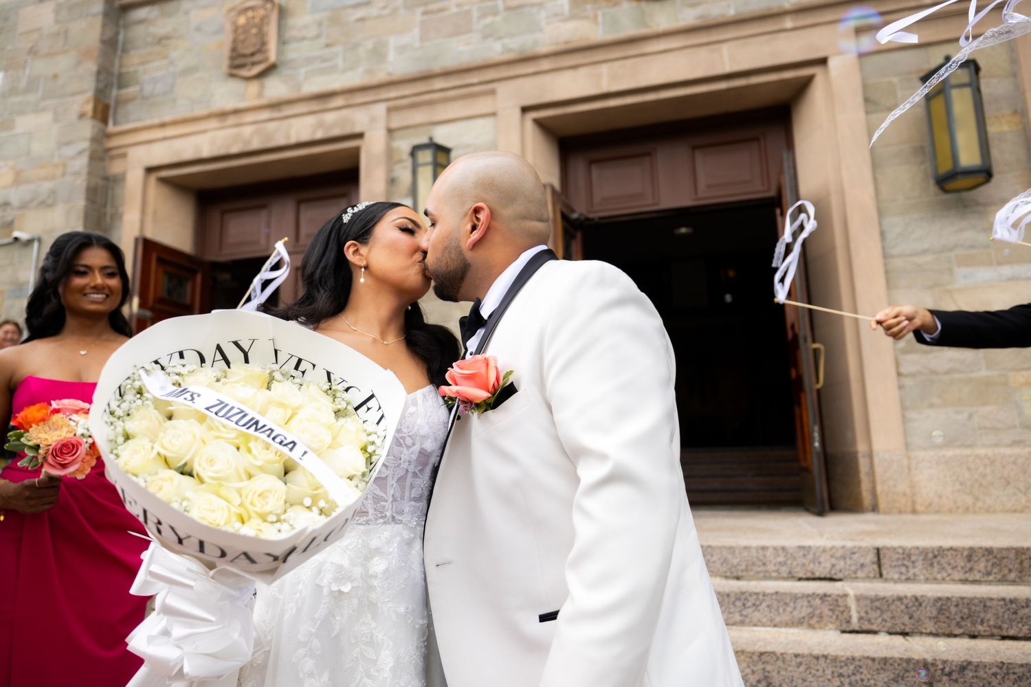 A couple shares a tender moment while celebrating their wedding day at a historic stone building.