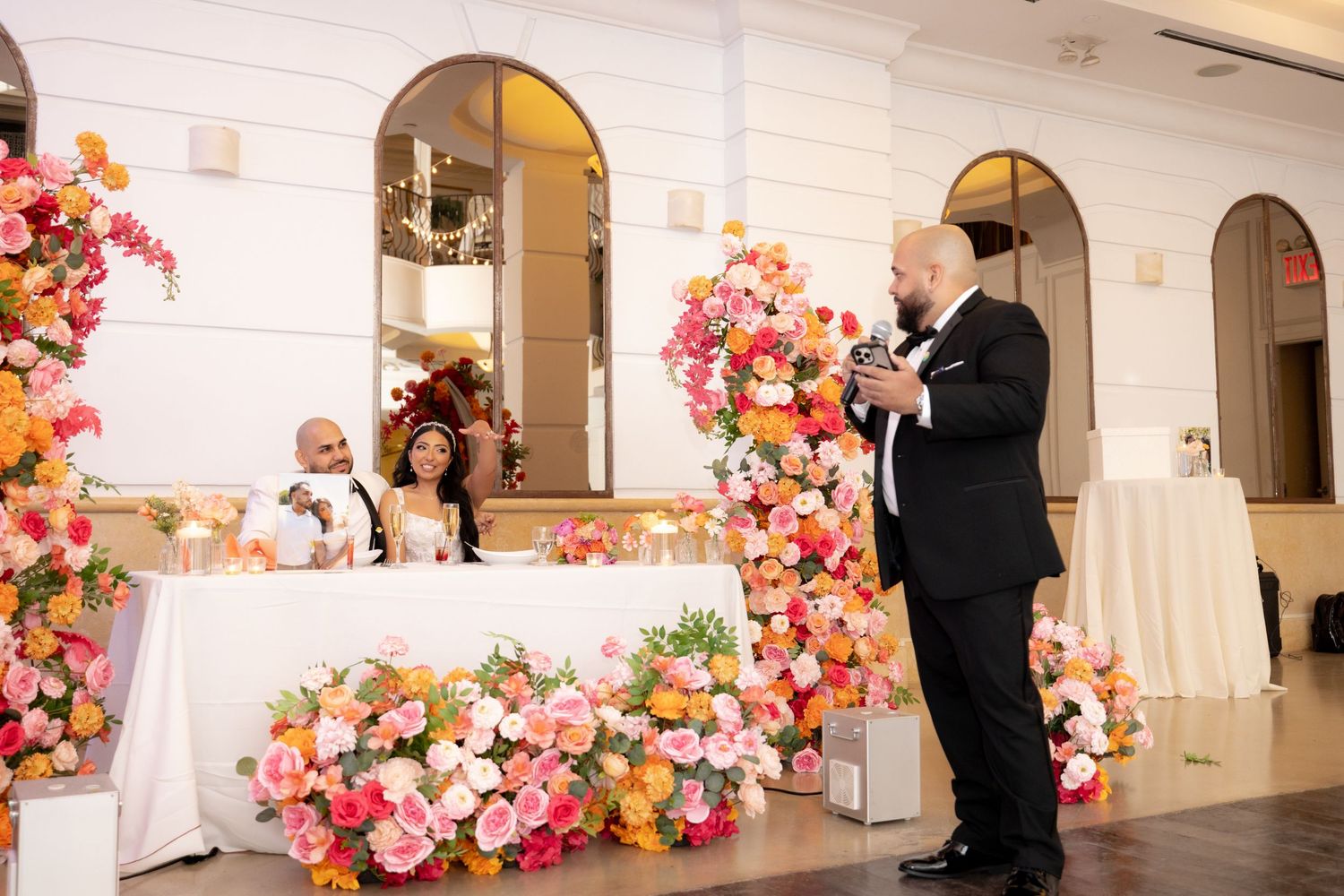 A wedding ceremony moment captured in a church with beautiful pink and orange floral arrangements adorning the space.