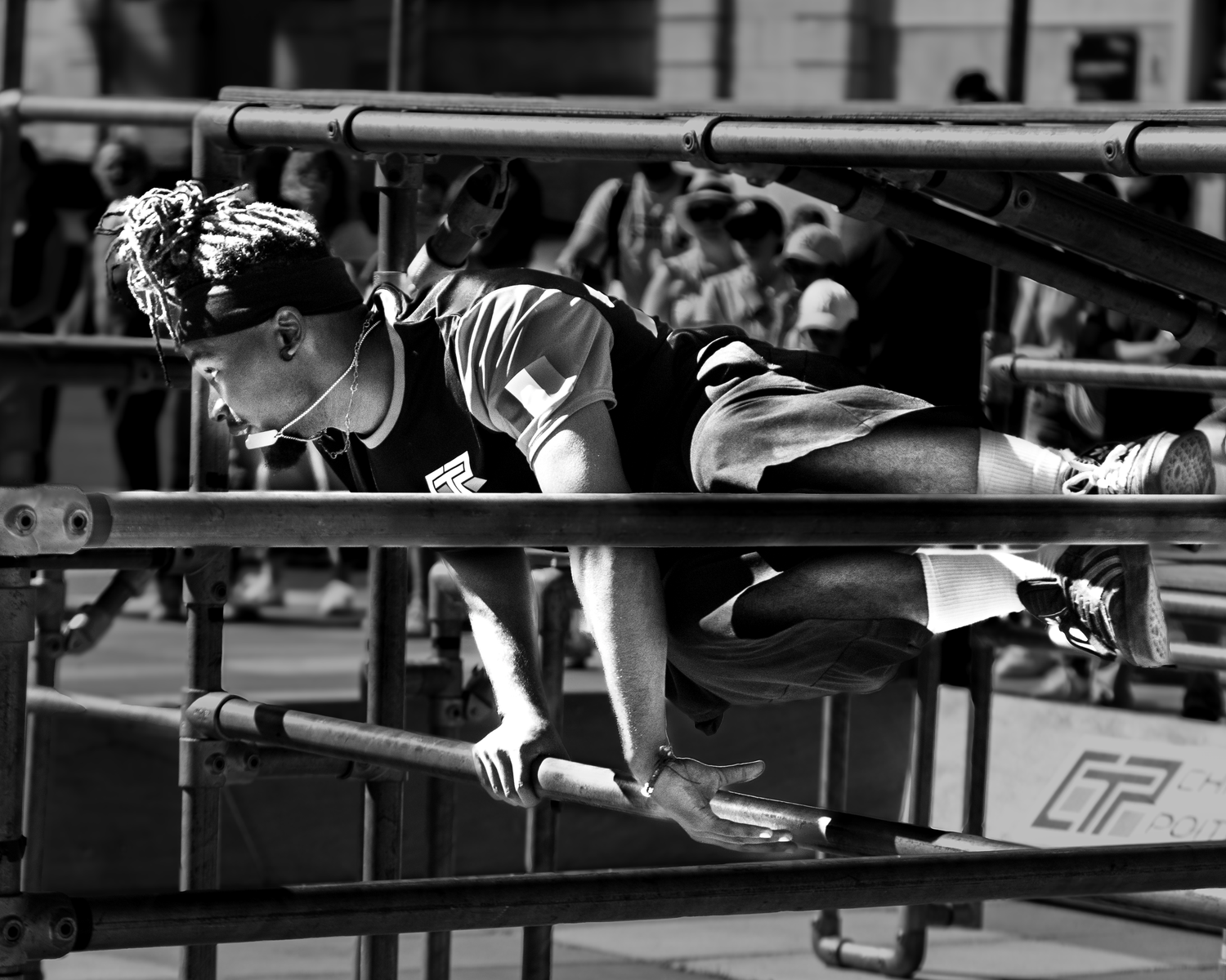 Black and white photo of athlete jumping over hurdles during track competition.