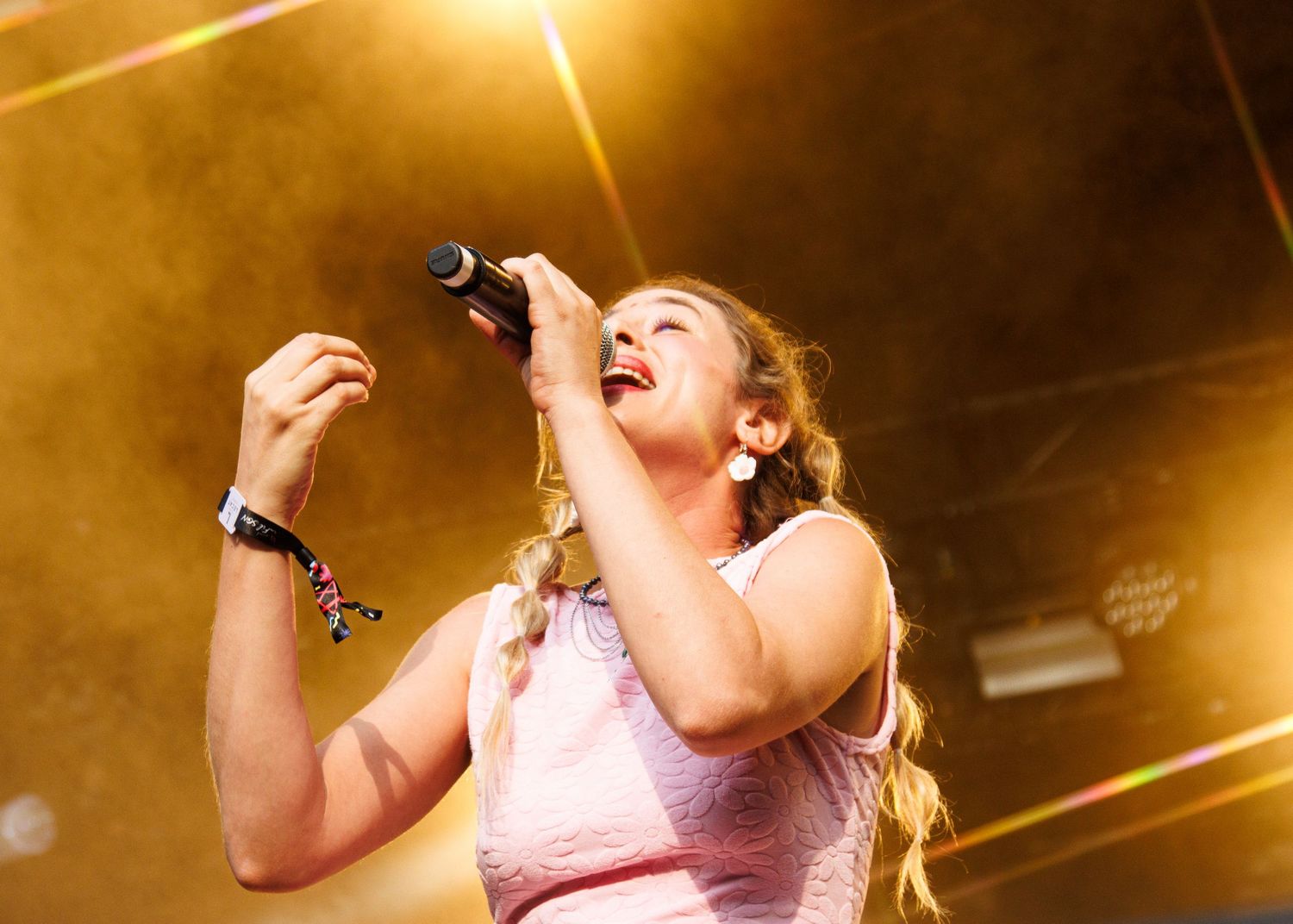 Singer performs passionately on stage with dramatic golden lighting effects in the background.