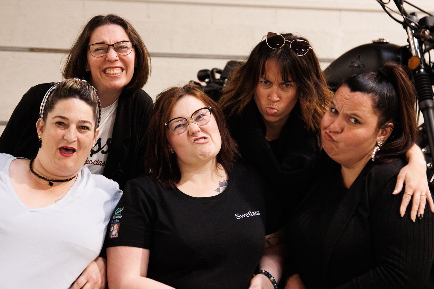 A cheerful group photo with friends smiling together against a light wall background.