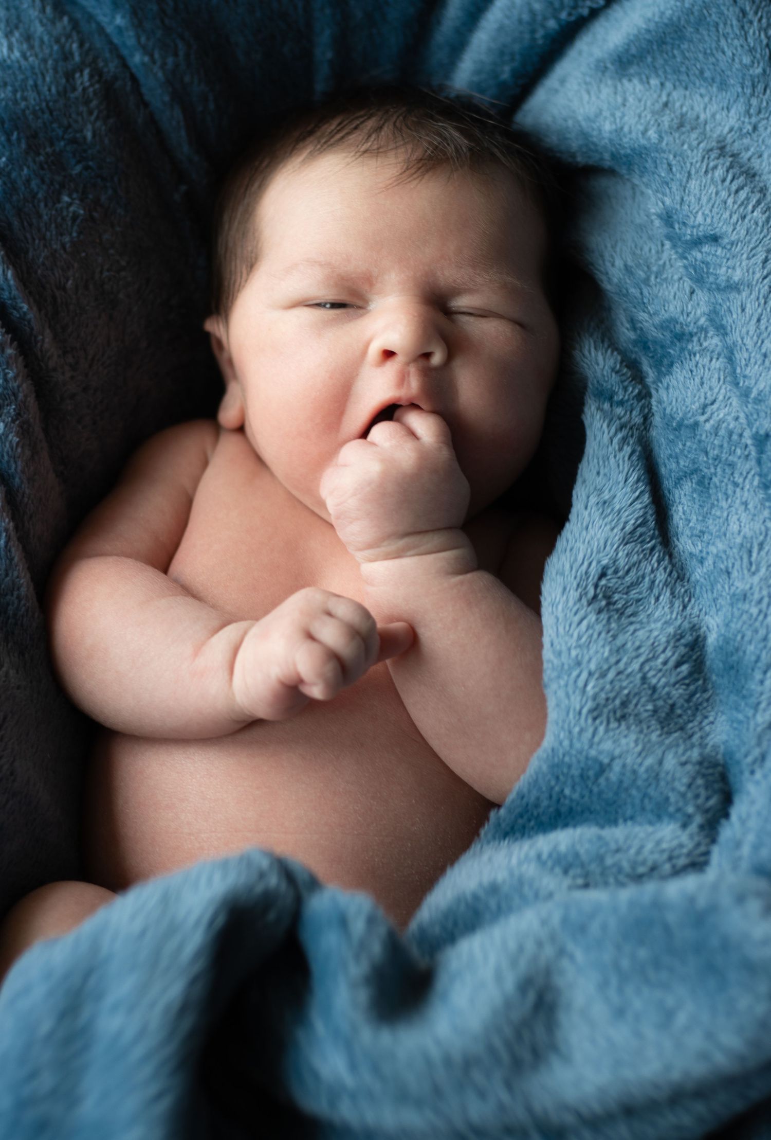 A sleeping infant rests peacefully on soft blue blankets.