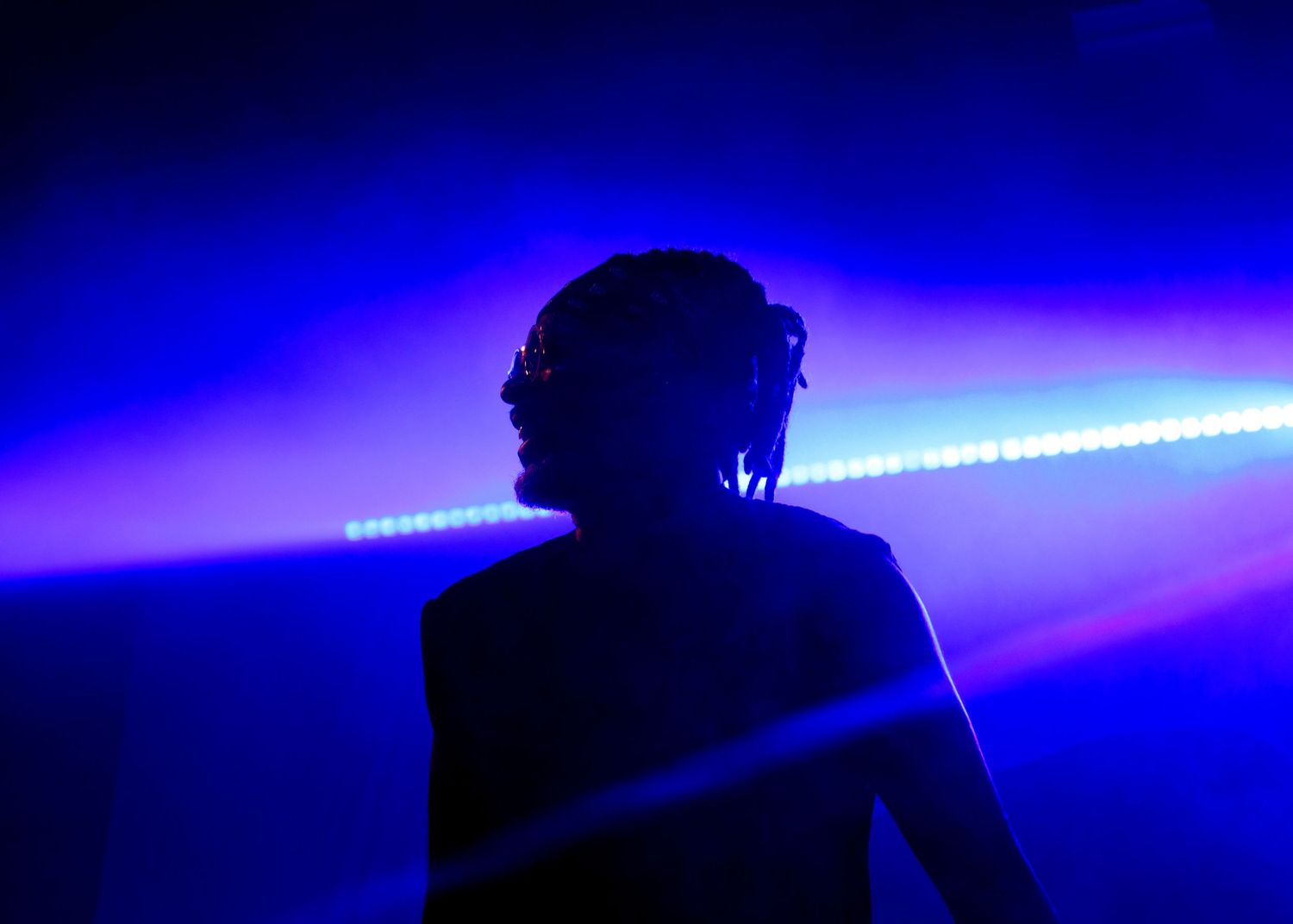 Silhouetted figure with blue neon lighting creates a dramatic cyberpunk atmosphere in dark setting.