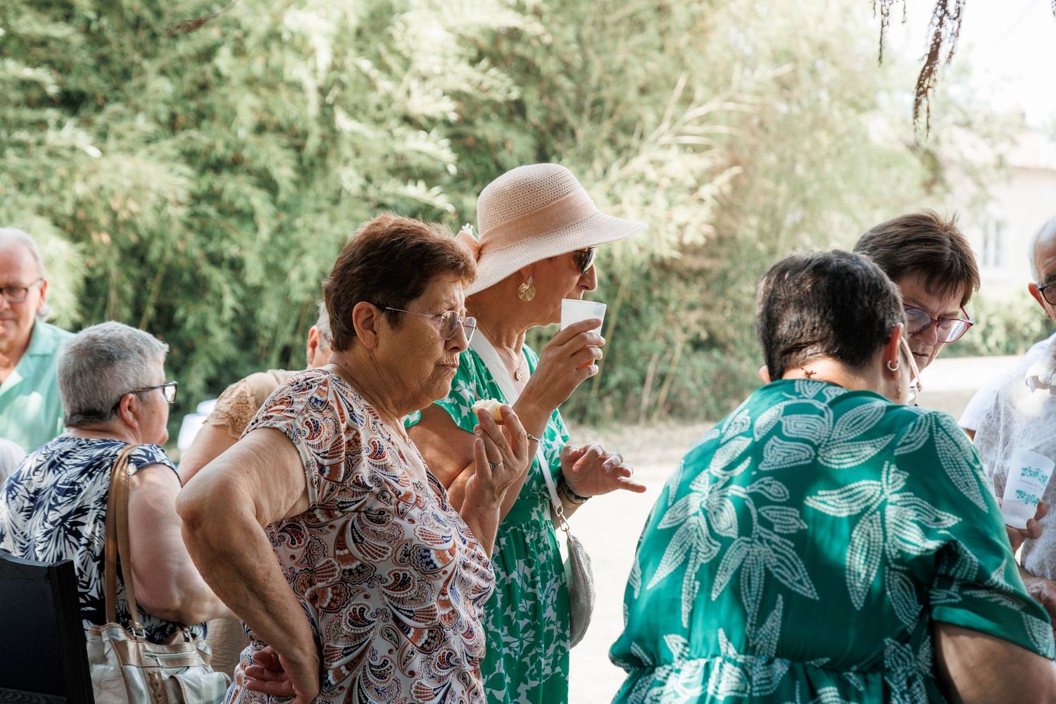 Elderly female wedding guests socializing outdoors in summer garden setting.