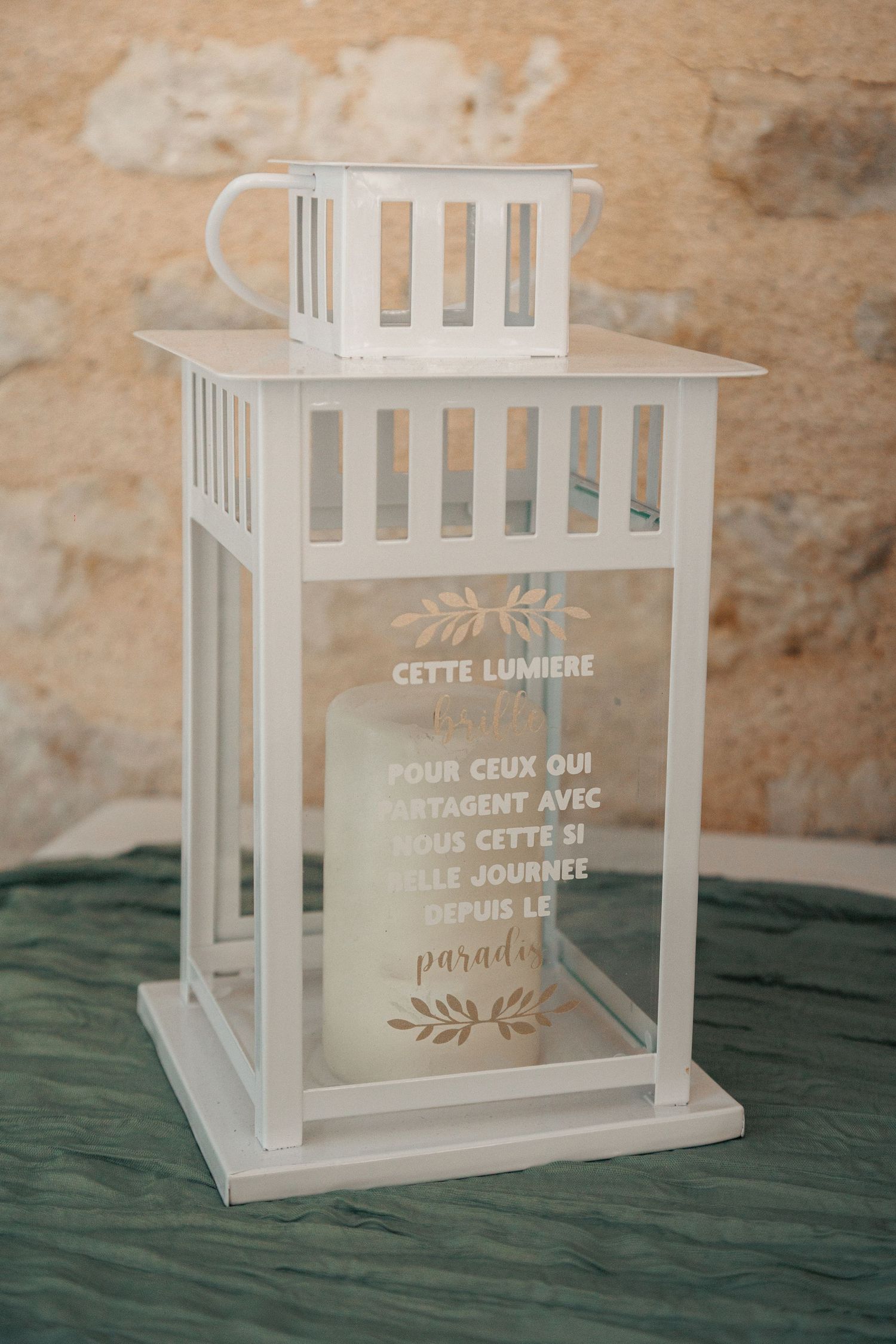 White decorative lantern with French memorial candle inscription at a wedding ceremony.