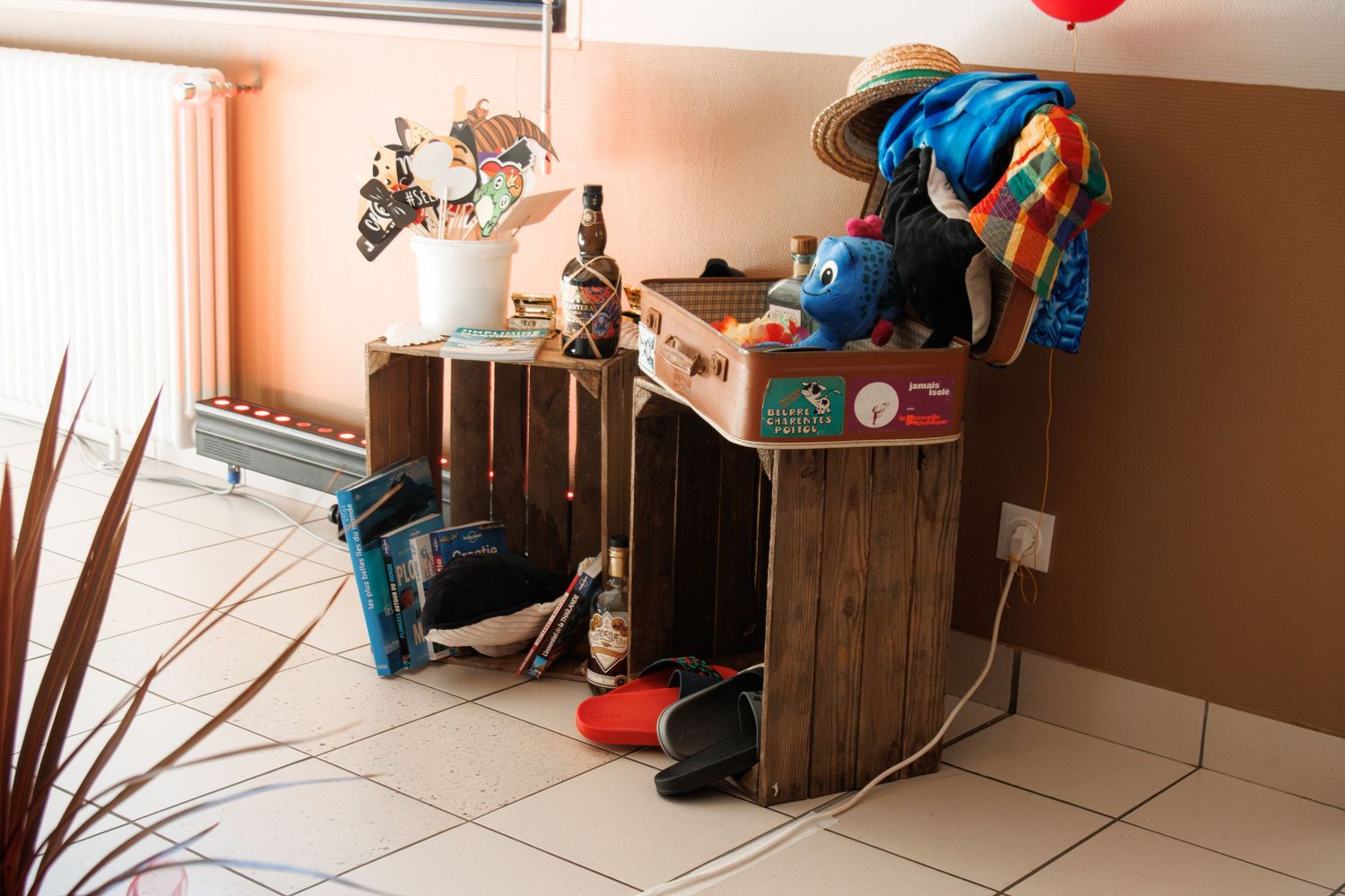 Colorful wedding photo booth corner with wooden crates, props, and festive decorations.
