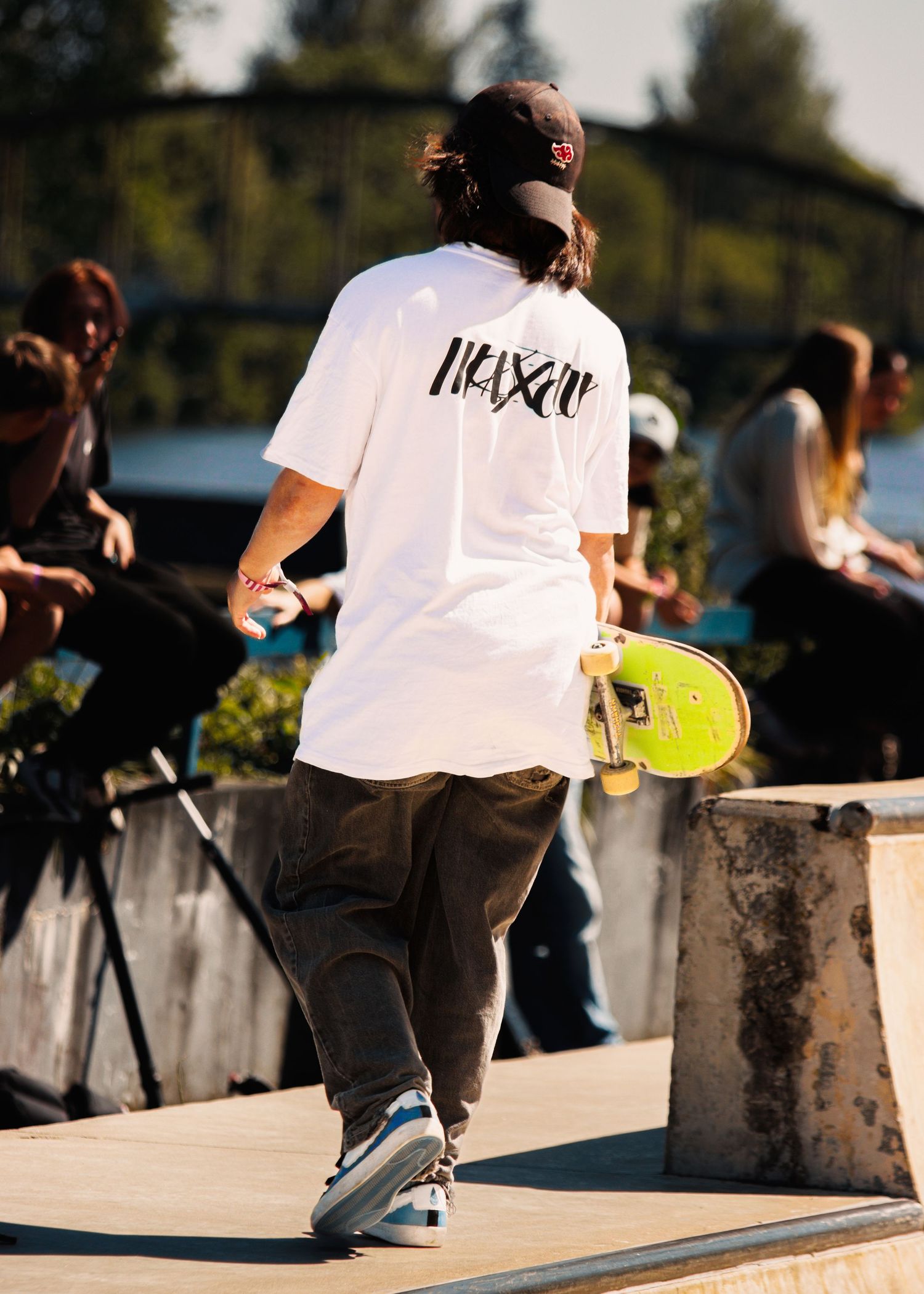 Skateboarders performing tricks at a concrete skate park during sunset.