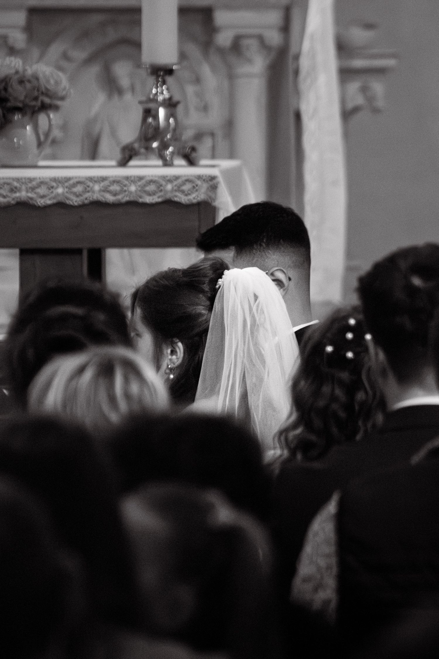 Black and white photo of a bride and groom at the altar during a church wedding ceremony.