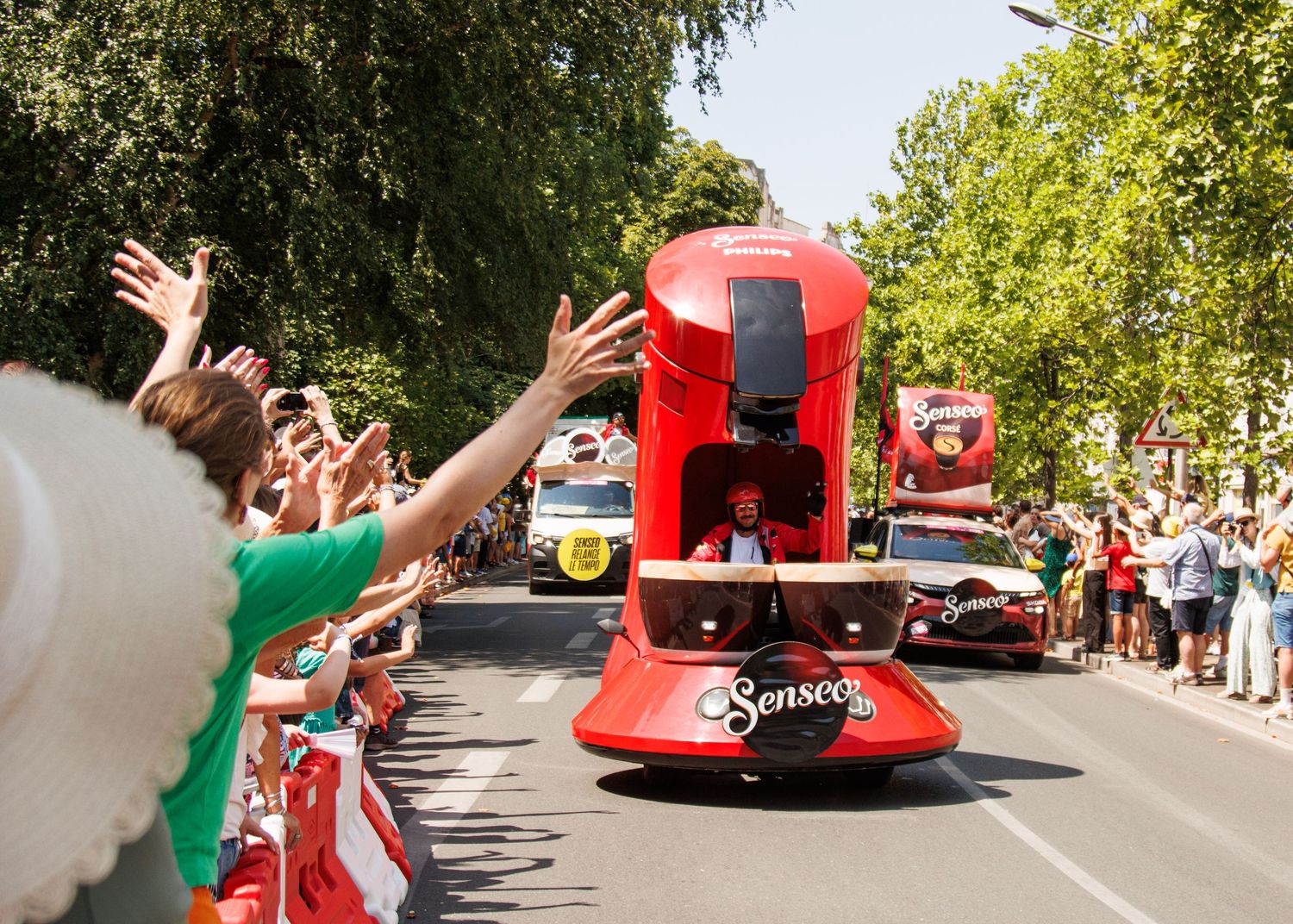 Large red promotional float shaped like a coffee maker draws cheers from excited parade spectators.