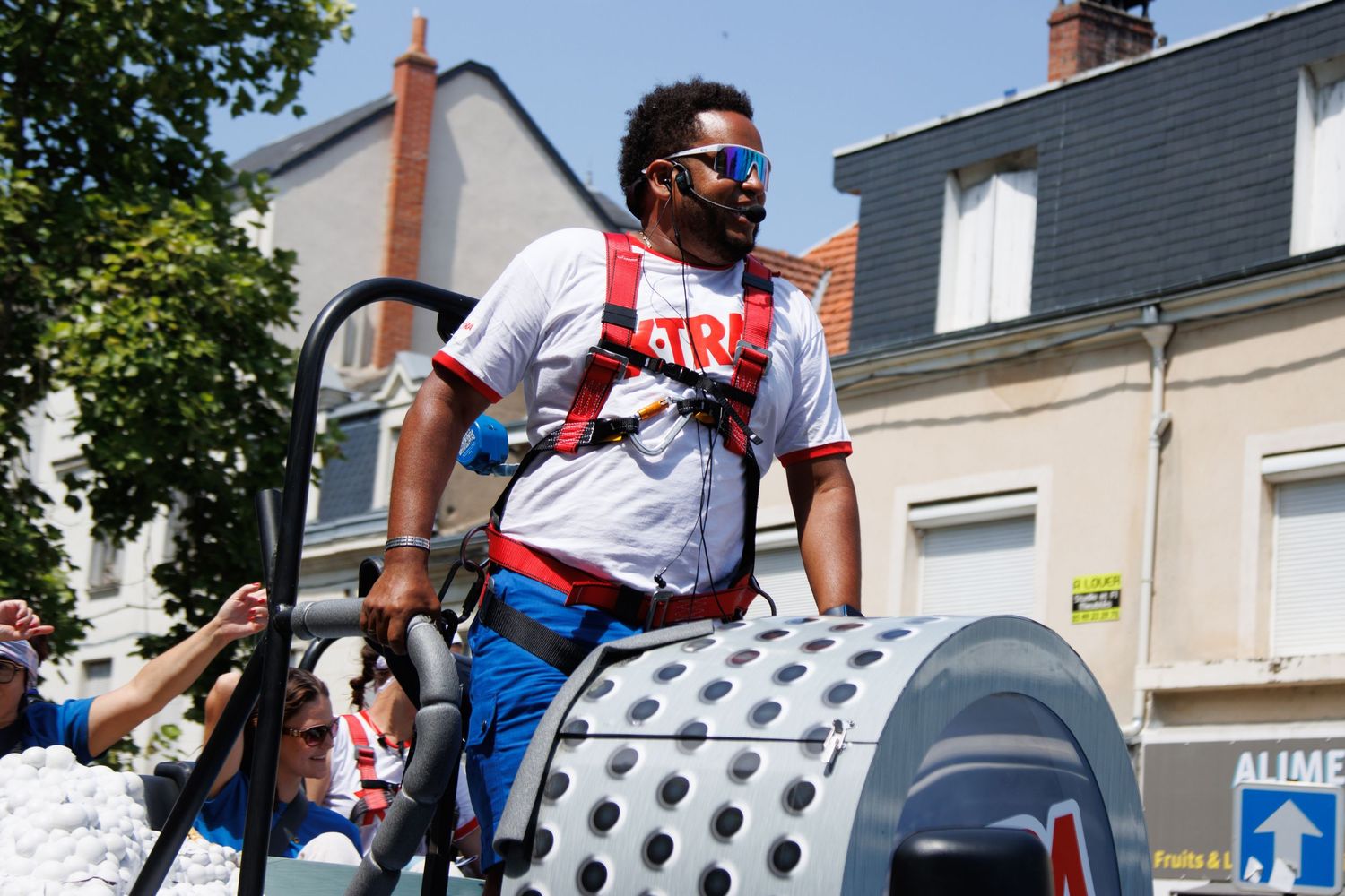 Performer standing on a decorated float during a summer street parade.