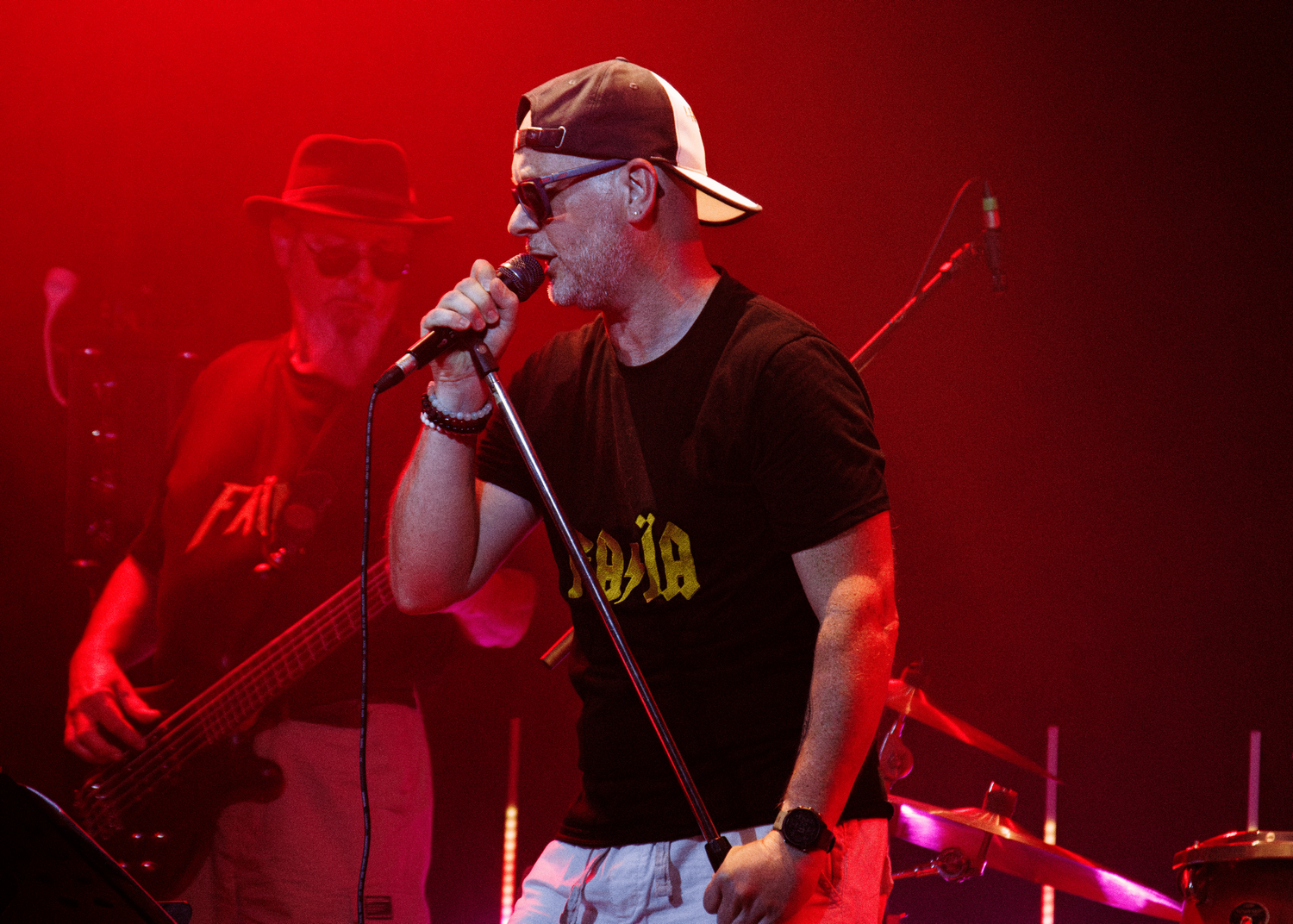 Musicians performing on stage bathed in intense red concert lighting.
