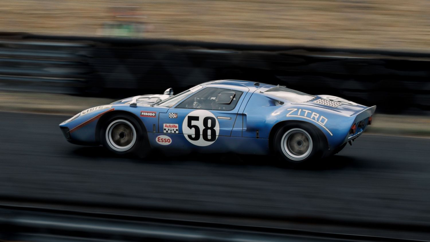 Vintage blue Ford GT40 race car with number 58 in motion on racetrack.