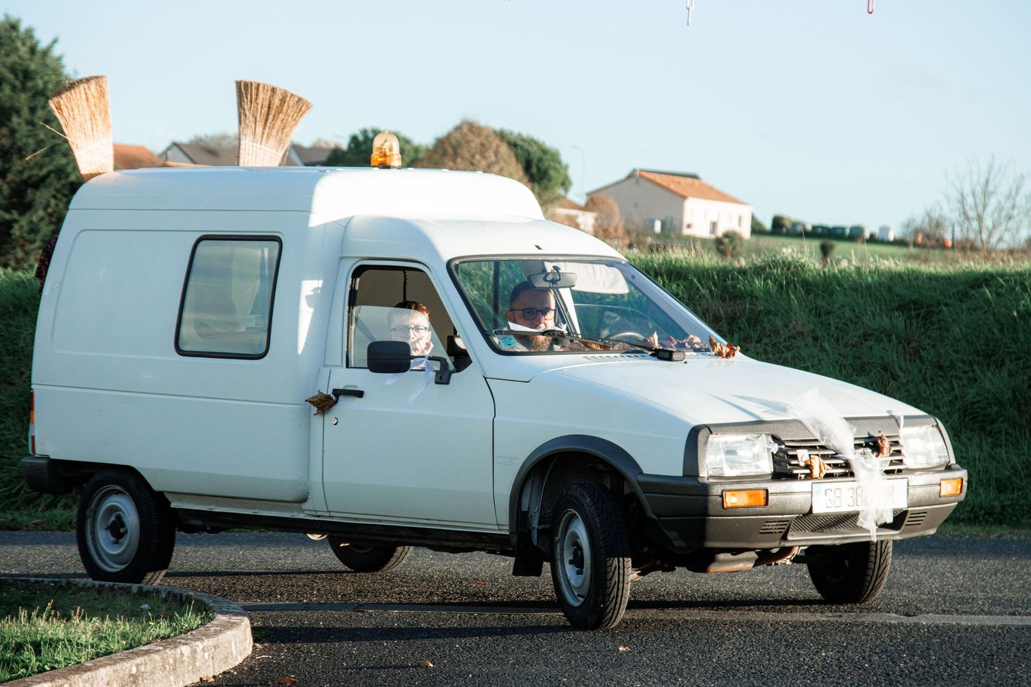 White Citroën C15 van driving on a road with baguettes visible through the rear window.