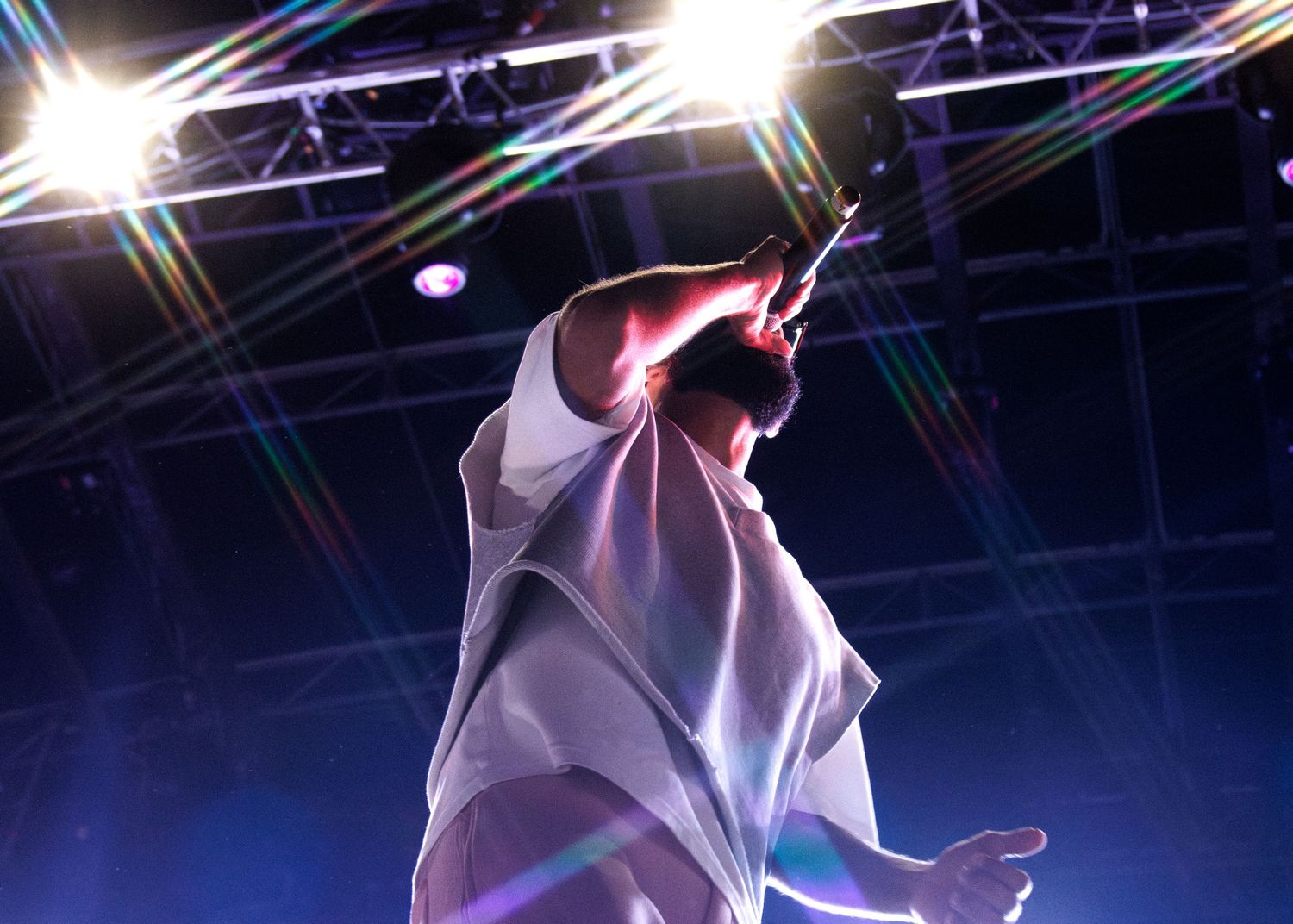 Performer in flowing white fabric dances under dramatic stage lighting with starburst effects.