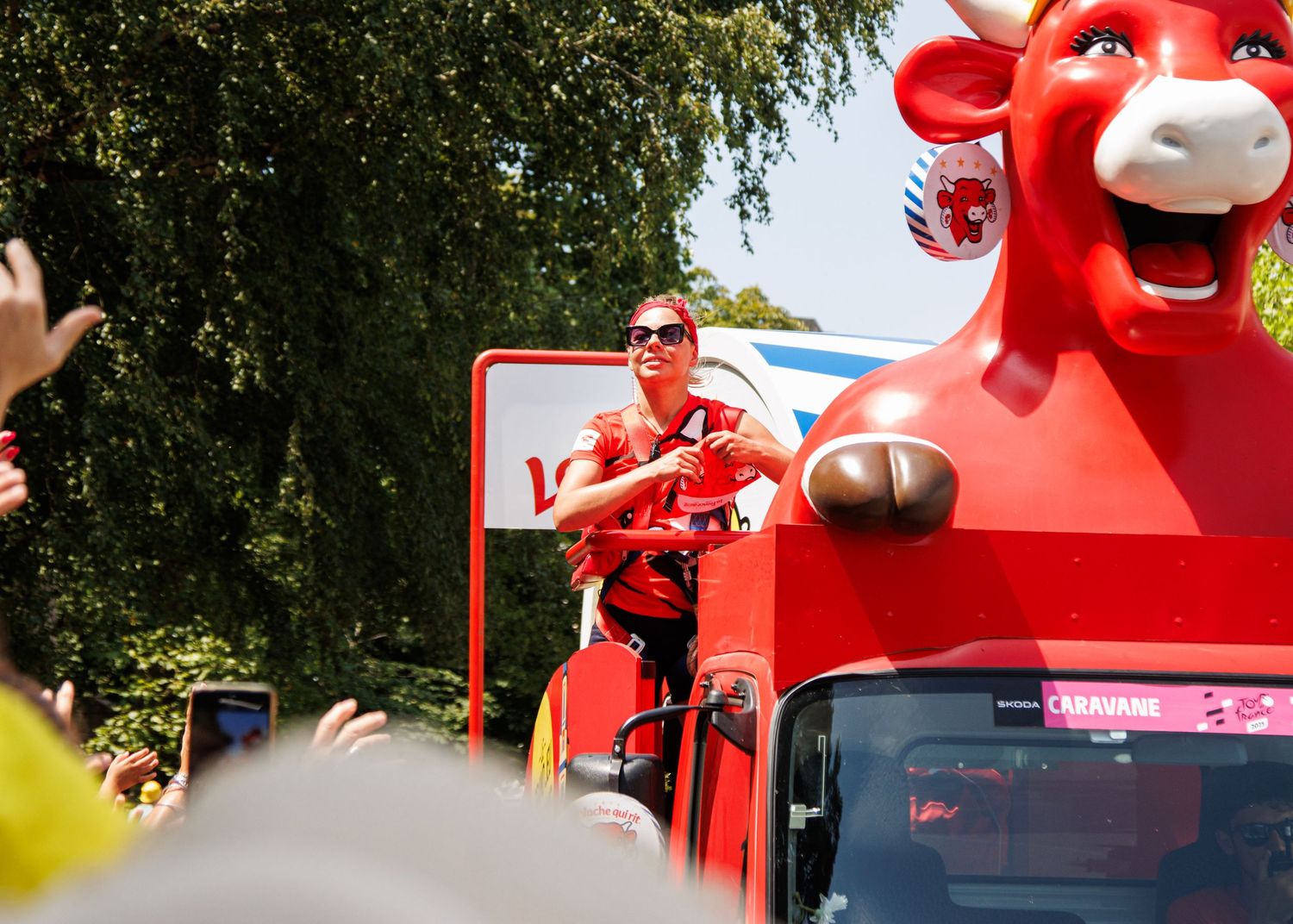 Red promotional float featuring a large cow mascot travels through a festive parade route.